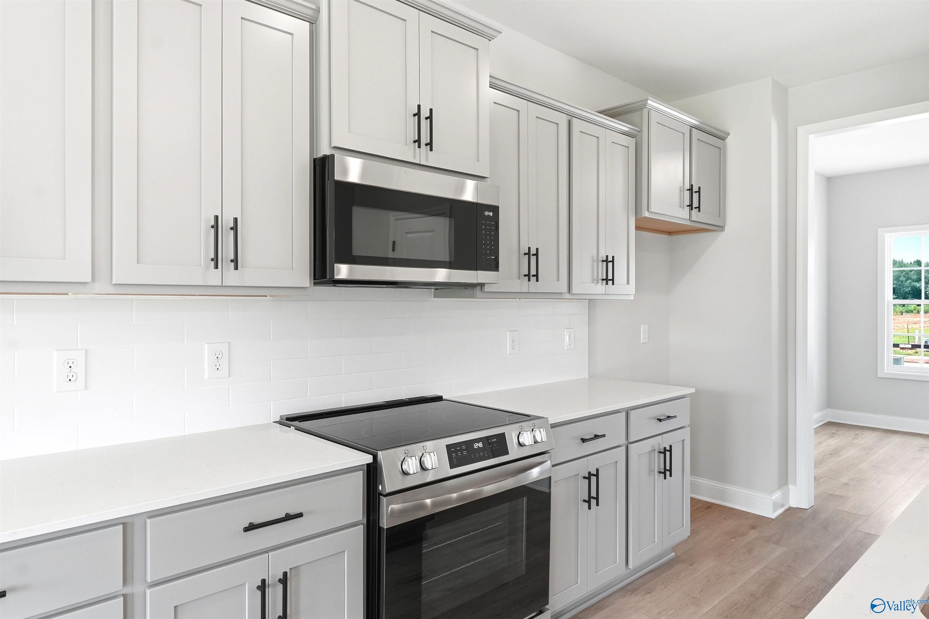 Modern kitchen with light gray cabinets, white subway tile, and stainless appliances in The Shelby A home, Wood Trail, Toney.