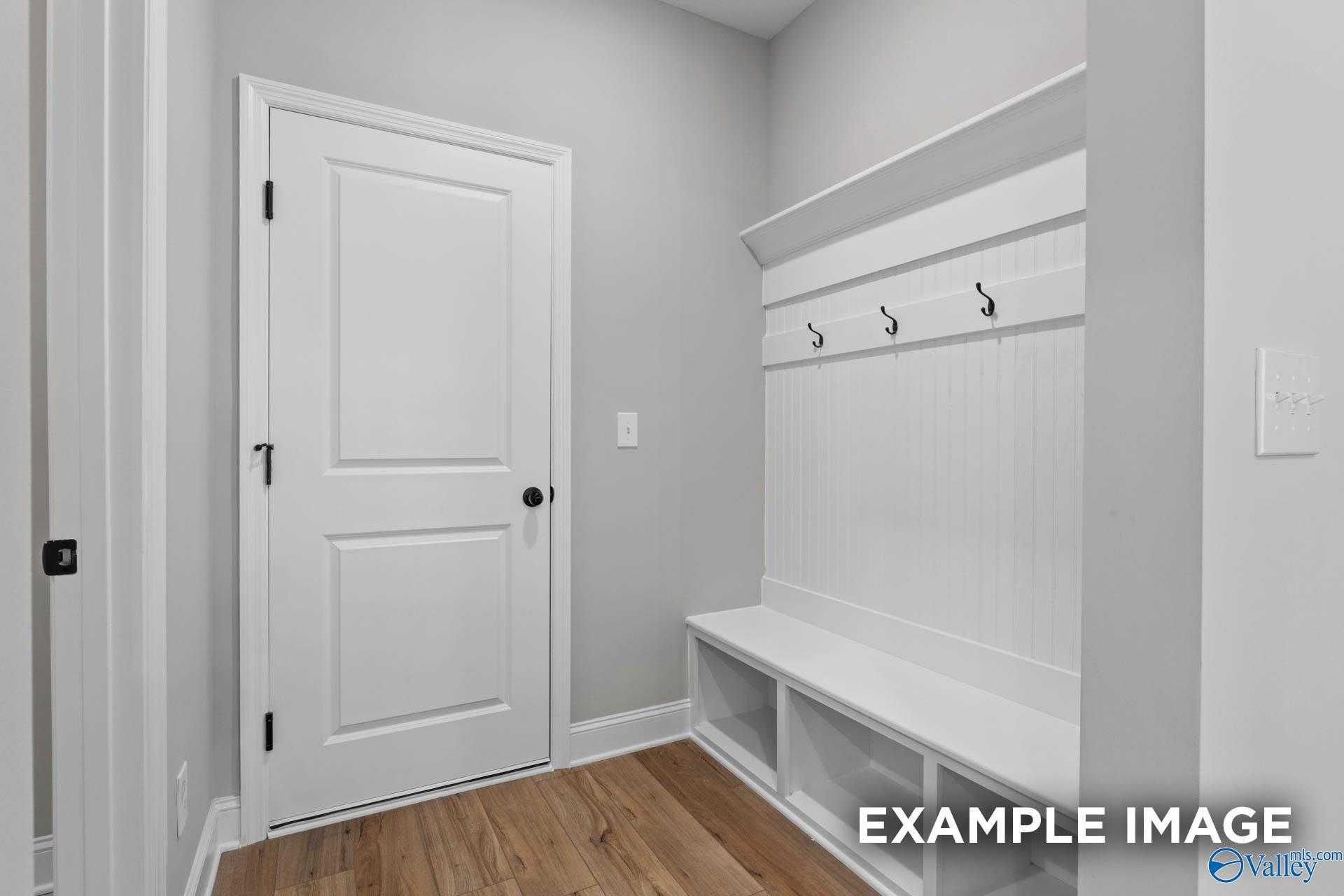 Functional mudroom with built-in white shiplap bench, coat hooks, and storage shelves in Davidson Homes The Montgomery B, Toney, Alabama