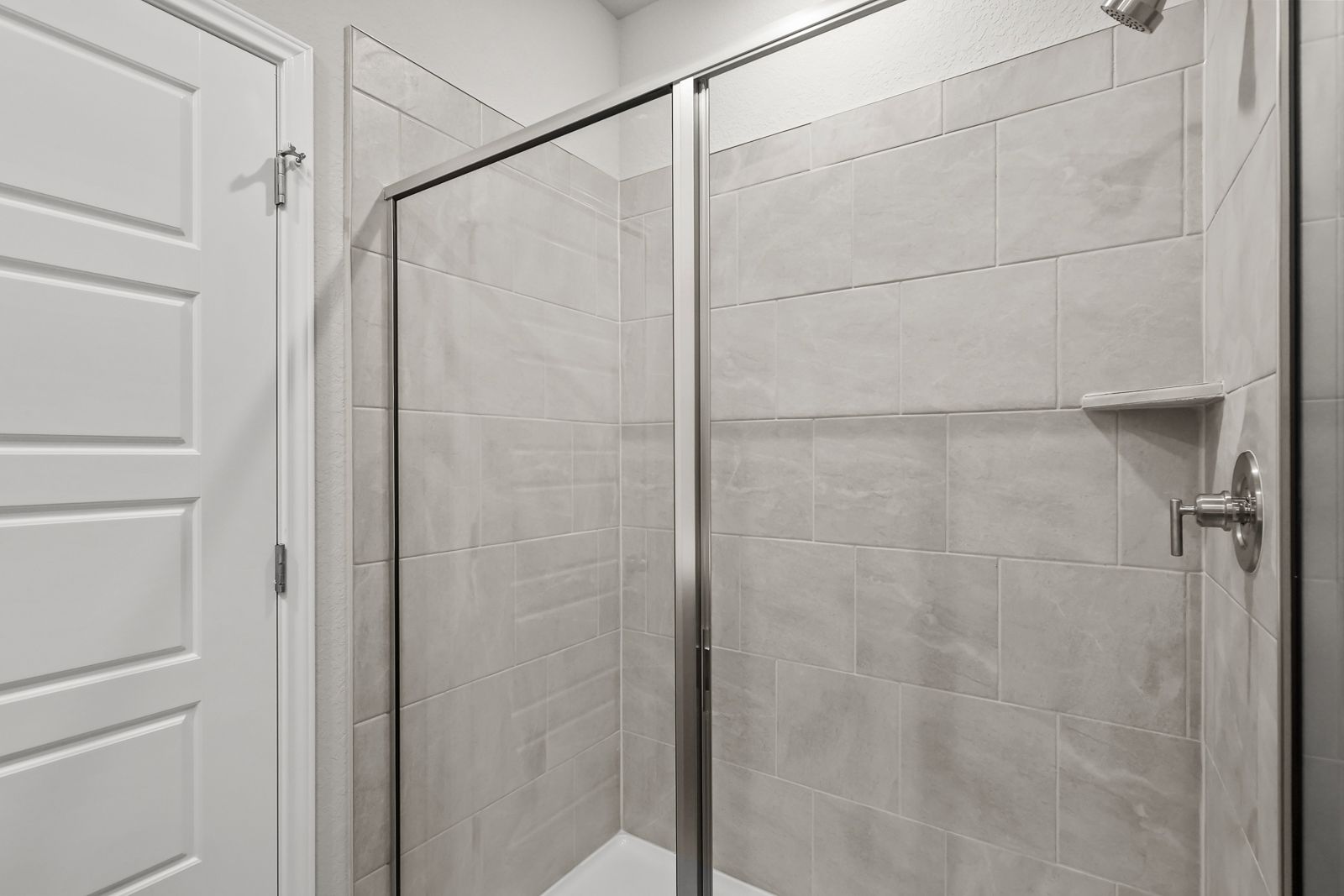 Walk-in shower with light gray subway tile and glass enclosure in the master suite of The Arroyo home design.