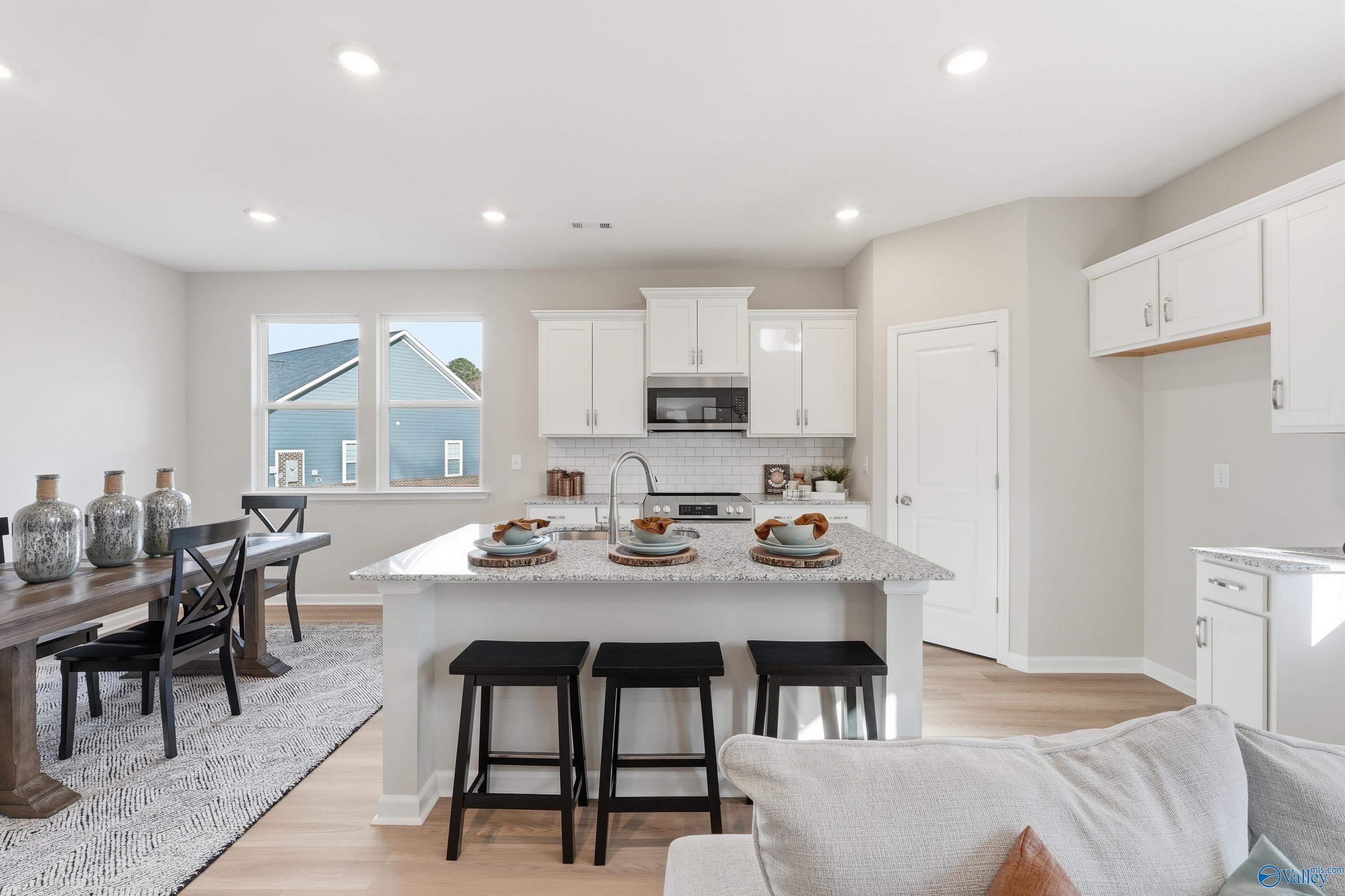 Modern open kitchen with granite island, white cabinets, stainless appliances in The Polaris 3-bedroom home, Fayetteville, TN