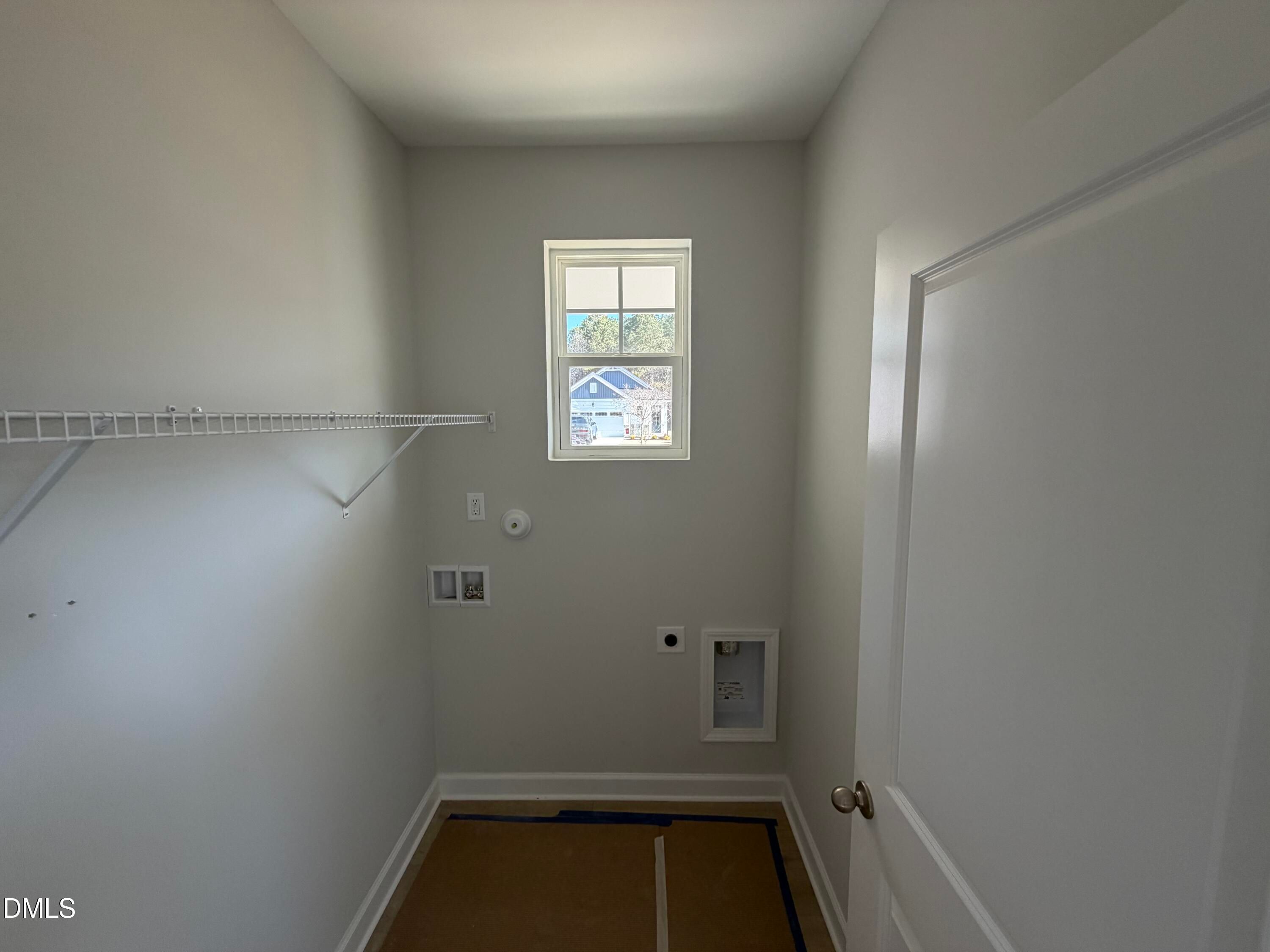 Bright laundry room with wire shelving, washer-dryer hookups, utility sink, and window in Davidson Homes The Carter C, Lillington, NC