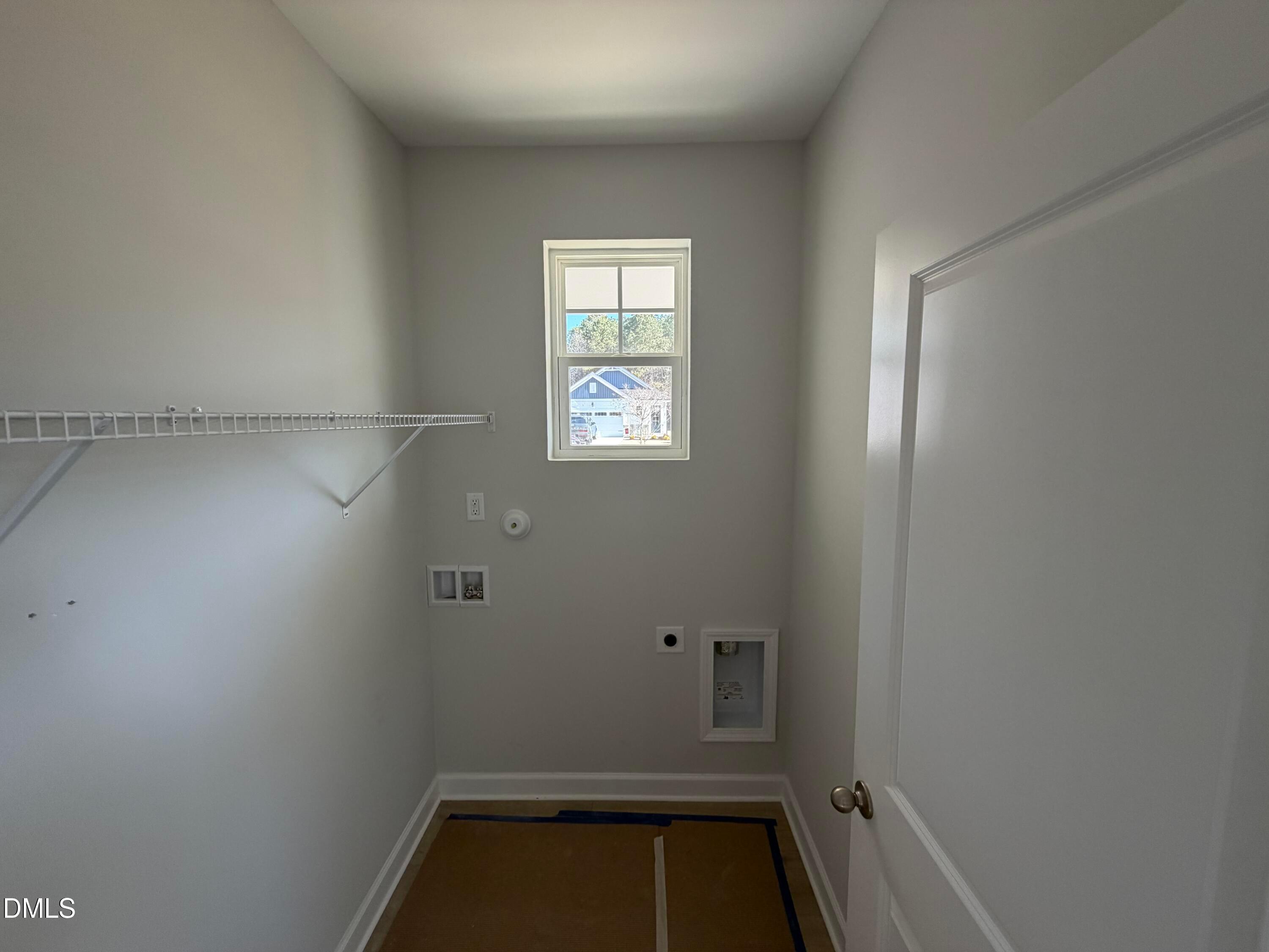 Bright laundry room with wire shelving, washer-dryer hookups, utility sink, and window in Davidson Homes The Carter C, Lillington, NC
