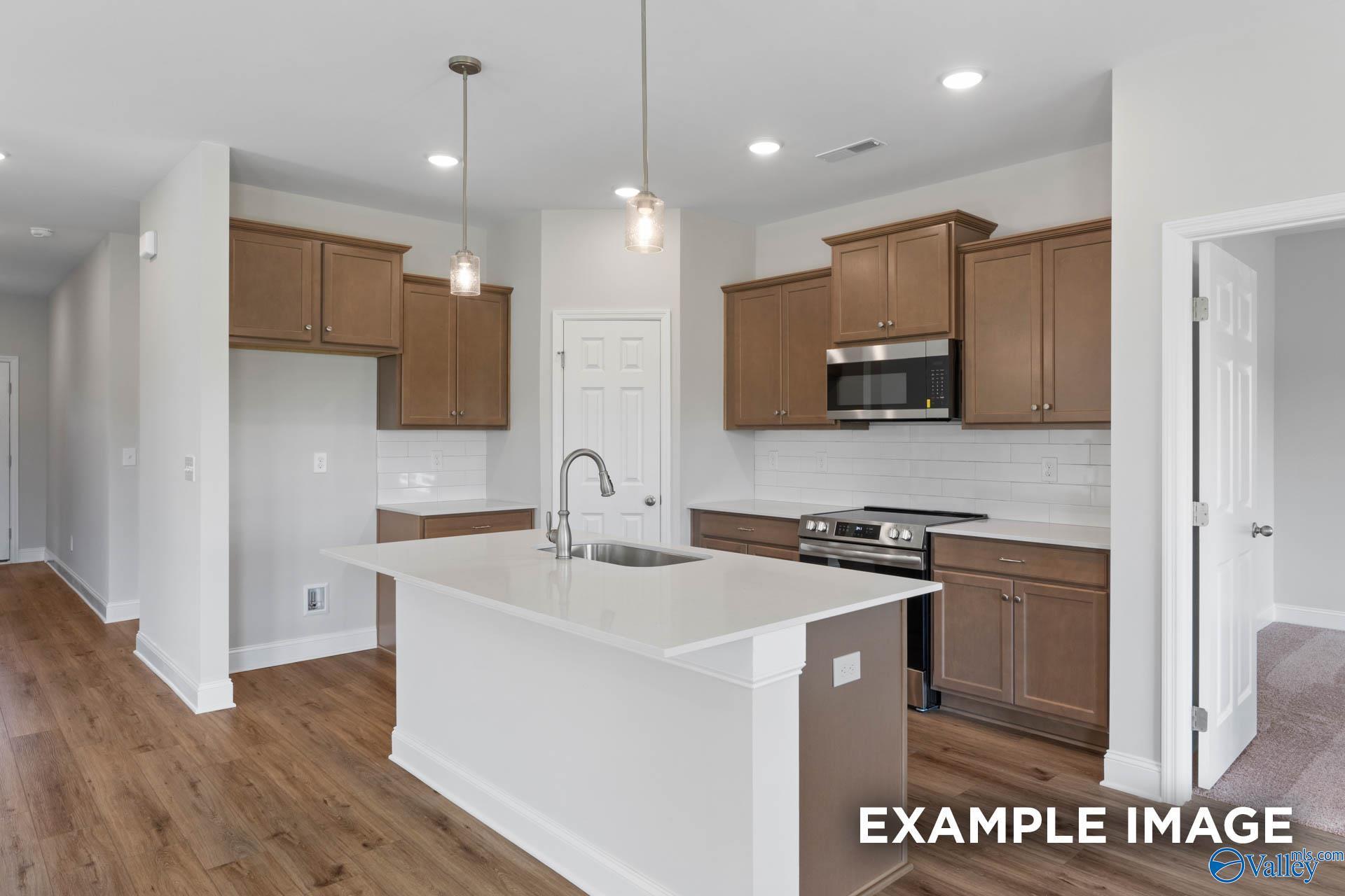 Modern open-concept kitchen featuring white quartz island, stainless appliances, and shaker cabinets in Davidson Homes The Franklin C, Meridianville, AL