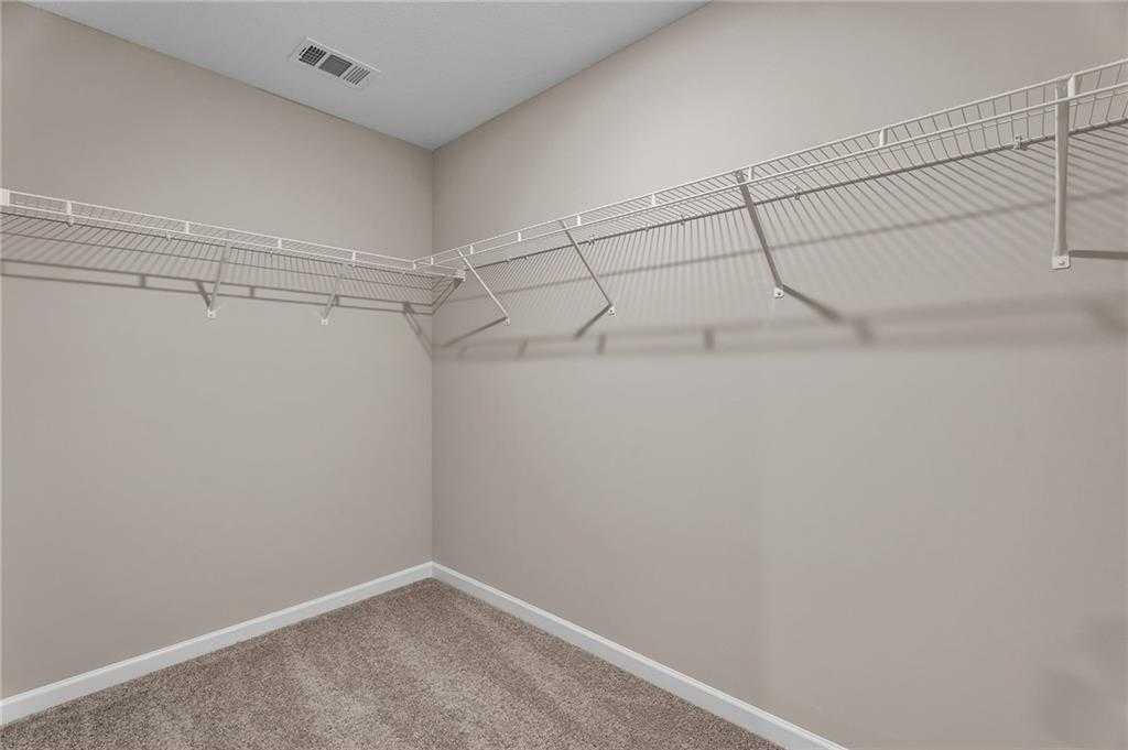 Spacious walk-in closet with wire shelving and beige walls in Davidson Homes The Bartlett, Phenix City, Alabama