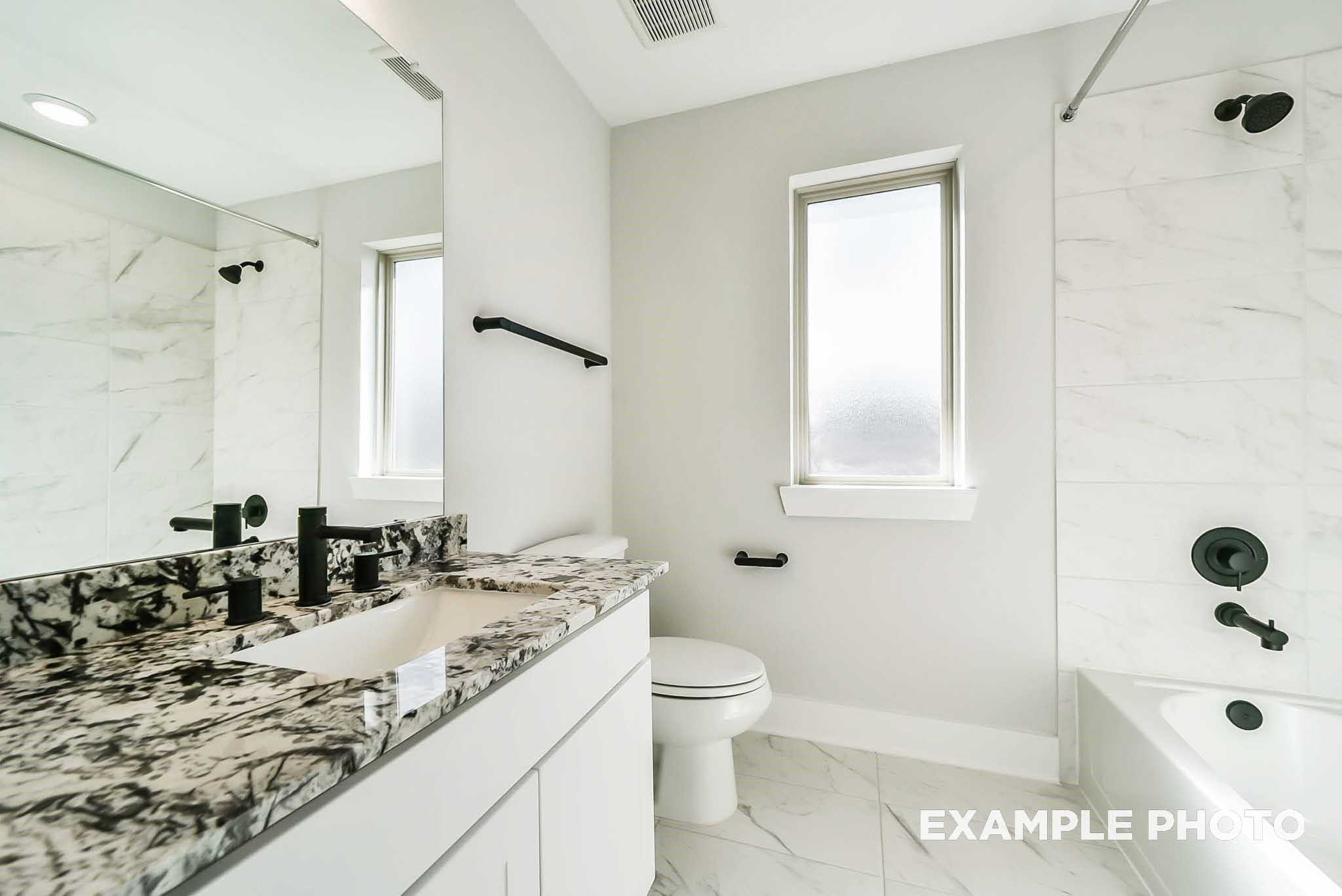 Modern master bathroom featuring dual vanity with quartz countertop, soaking tub, glass shower, and black fixtures in Davidson Homes The Philip C, Rosharon, Texas