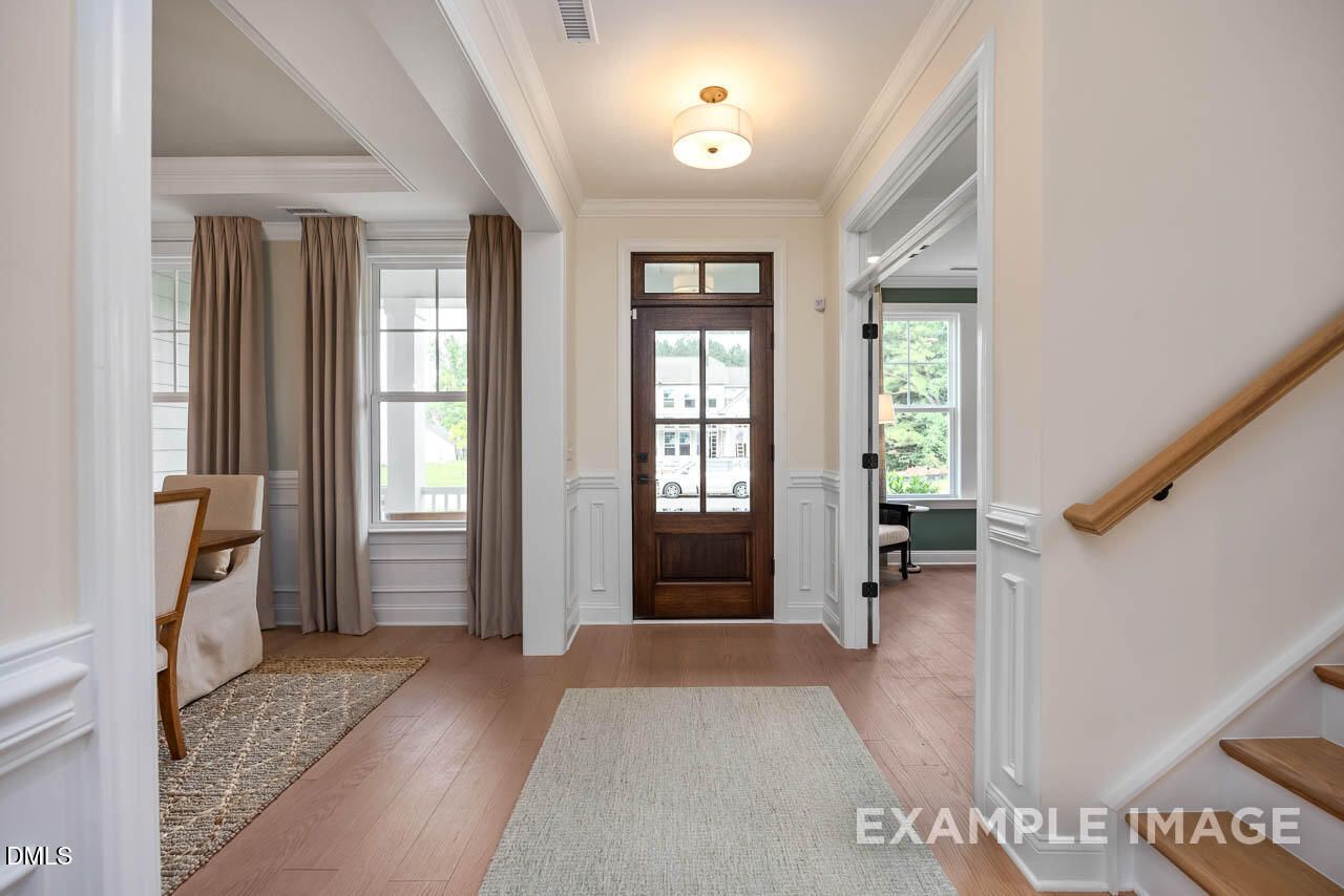 Elegant foyer with hardwood floors, wooden front door, and oak staircase in Davidson Homes The Crawford D, Angier, NC