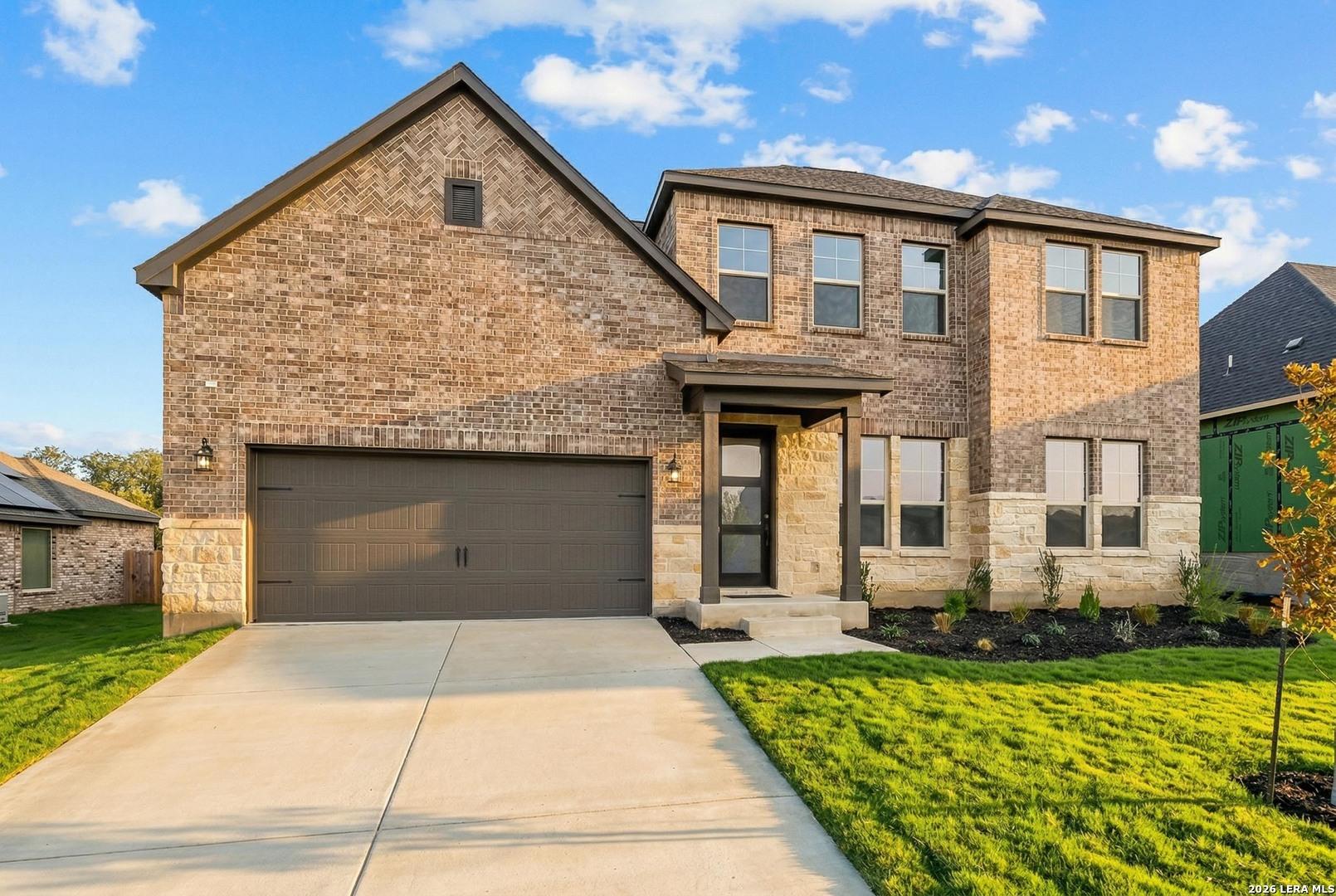 Two-story brick and stone home with a 2-car garage at The Reserve at Potranco Oaks in Castroville, Texas.