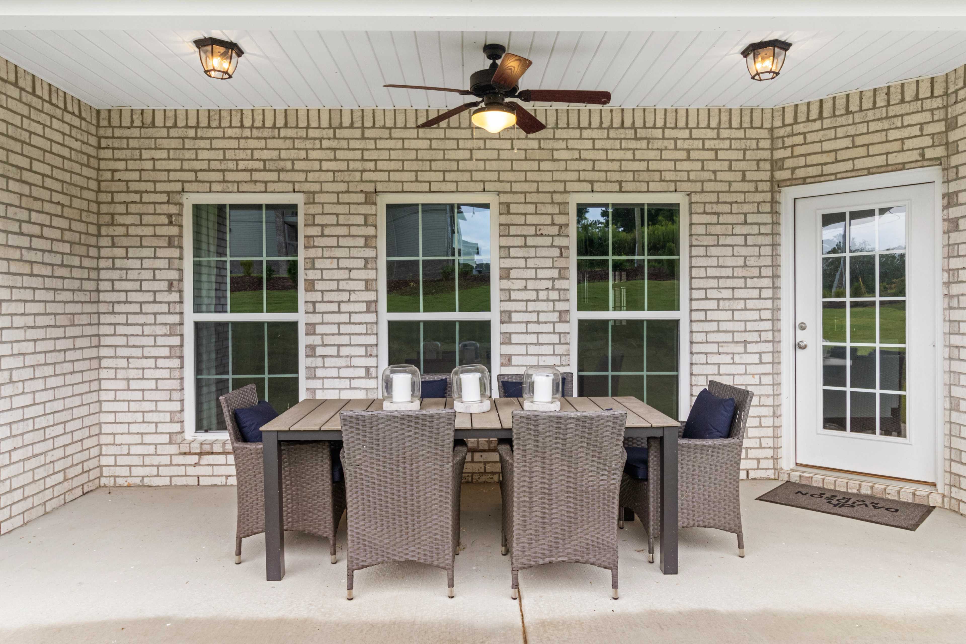 Covered patio with wicker dining table, chairs, ceiling fans, and brick walls at North Ridge in Cullman Alabama