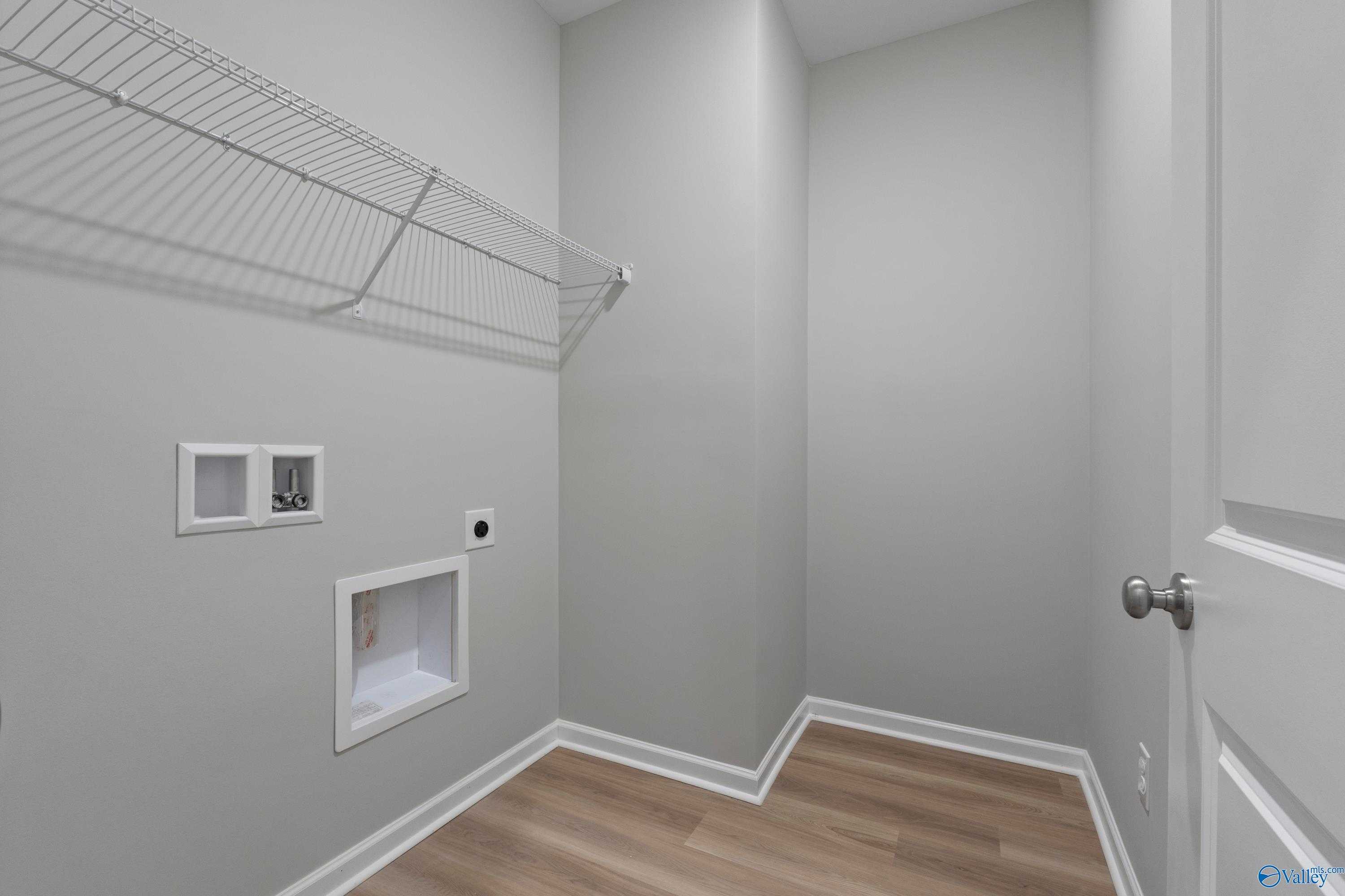 Spacious laundry room with wire shelving, washer/dryer hookups, gray walls in The Polaris 3-bedroom home by Davidson Homes, Fayetteville, TN