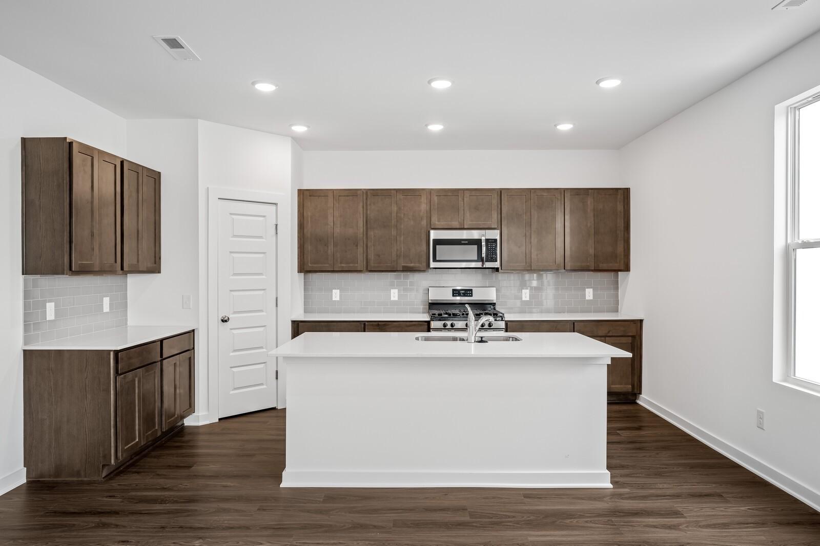 Modern kitchen featuring white island with sink, shaker cabinets, stainless steel appliances in The Logan C floor plan, White House, TN