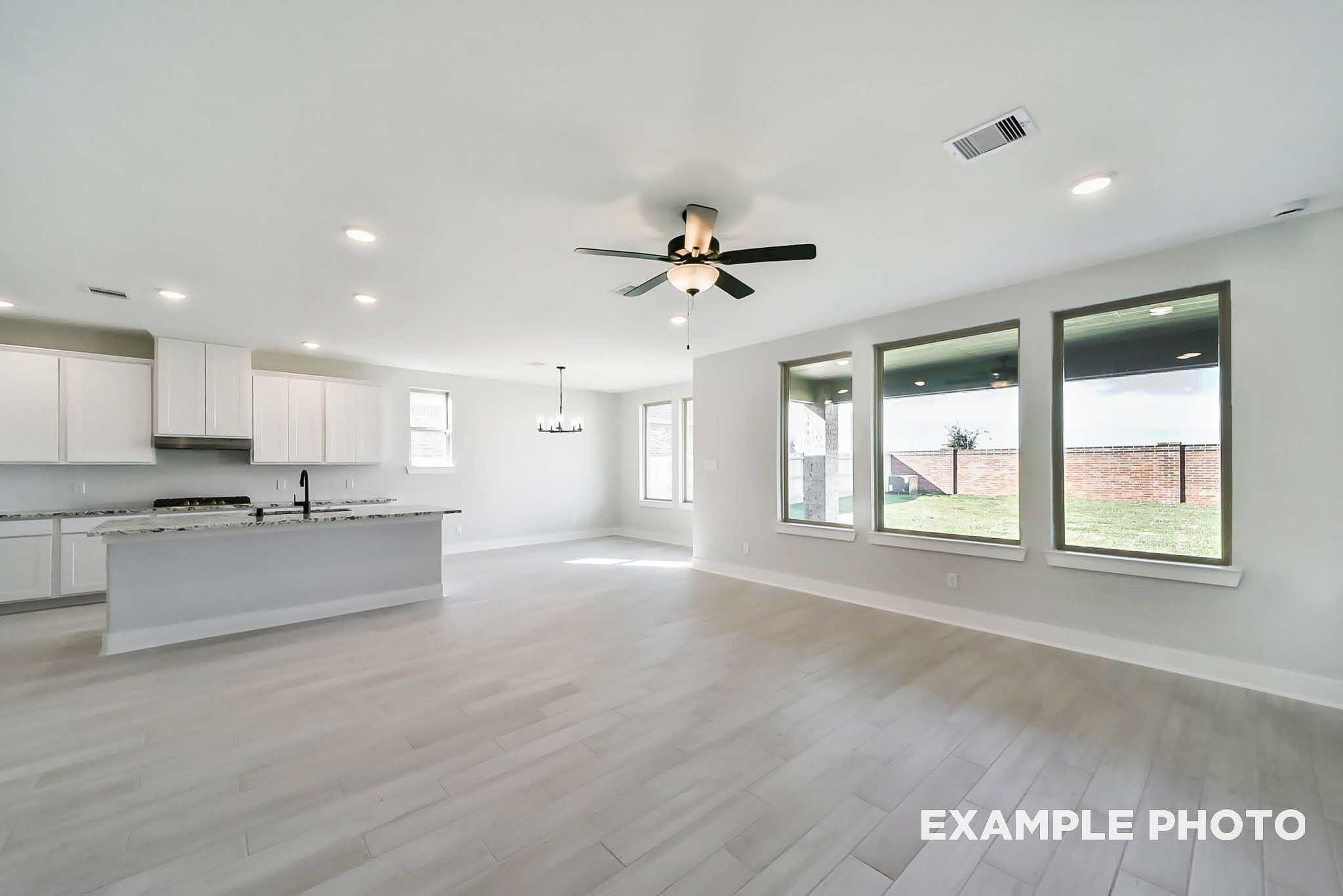 Open-concept kitchen with white cabinets, large island, and ceiling fan in Davidson Homes The Philip C floor plan, Rosharon, Texas