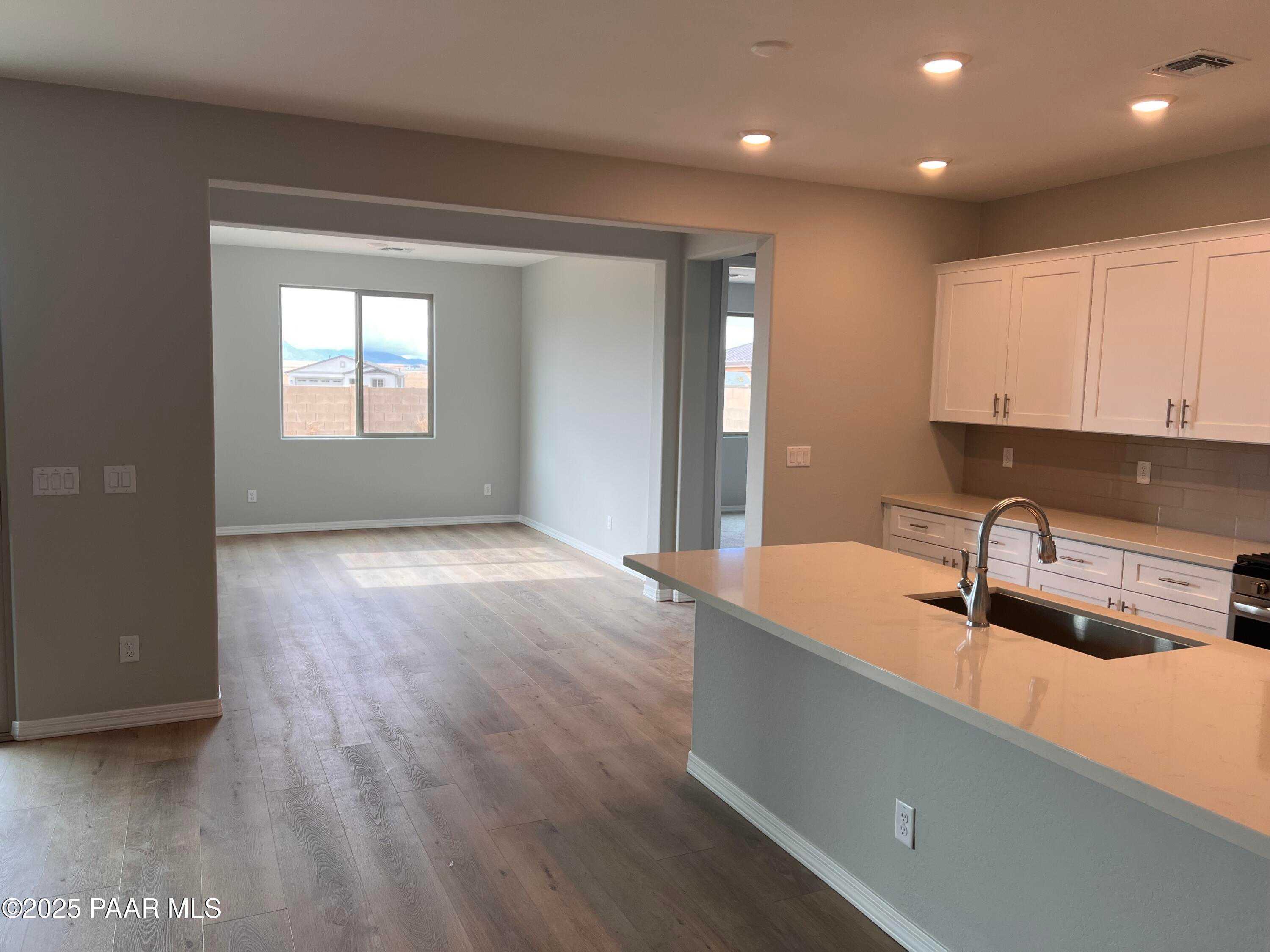 Open-concept kitchen with white cabinets, quartz island sink, and mountain-view living area in Davidson Homes Inspiration B, Prescott Valley, AZ