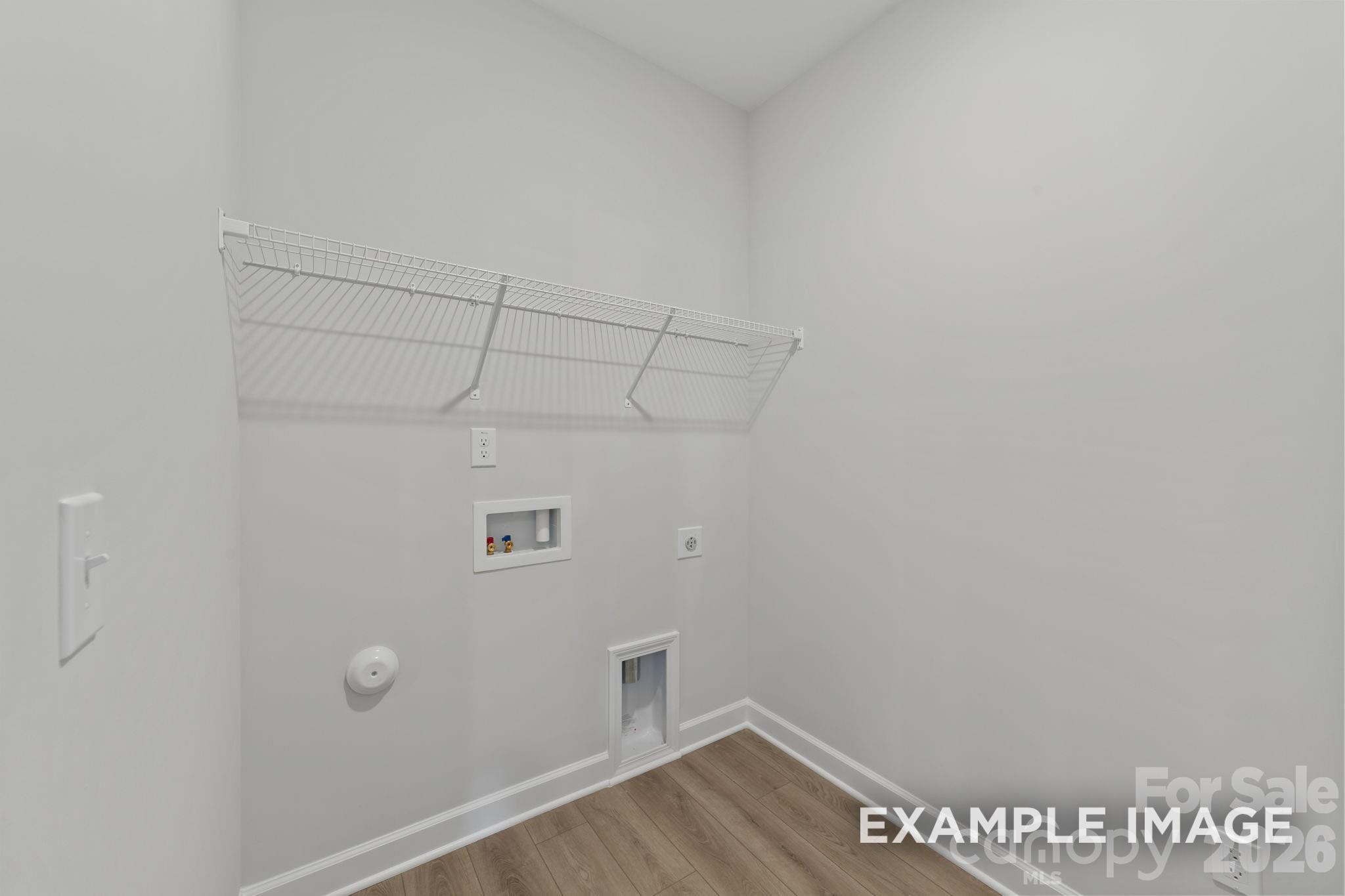 Laundry room with wire shelving and utility hookups in a Davidson Homes Magnolia B floor plan in Windgate, Mooresville.