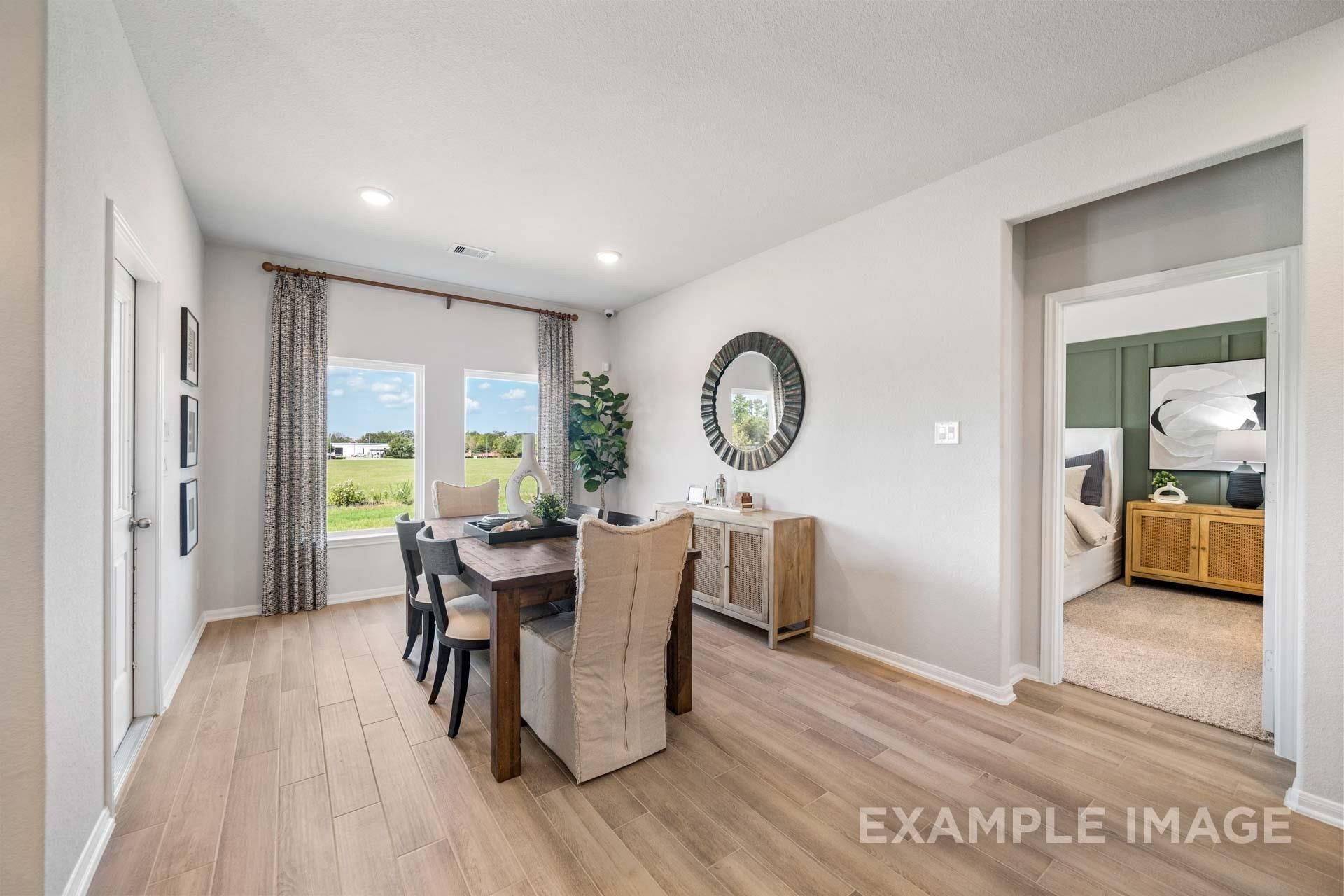 Elegant dining room with wooden table, upholstered chairs, large windows to green views in The Acadia A 4-bedroom home, Davidson Homes, Lago Mar, Texas City