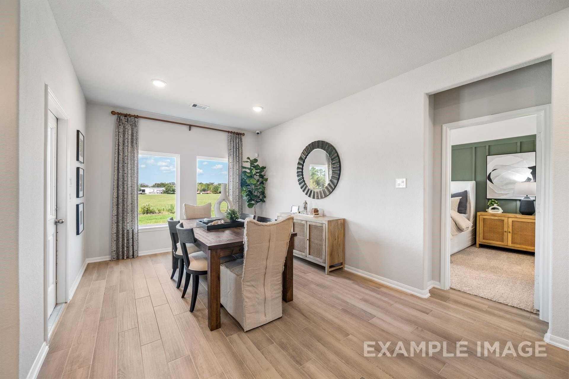 Elegant dining room with wooden table, round mirror, and windows overlooking fields in Davidson Homes The Acadia A, Lago Mar, Texas City