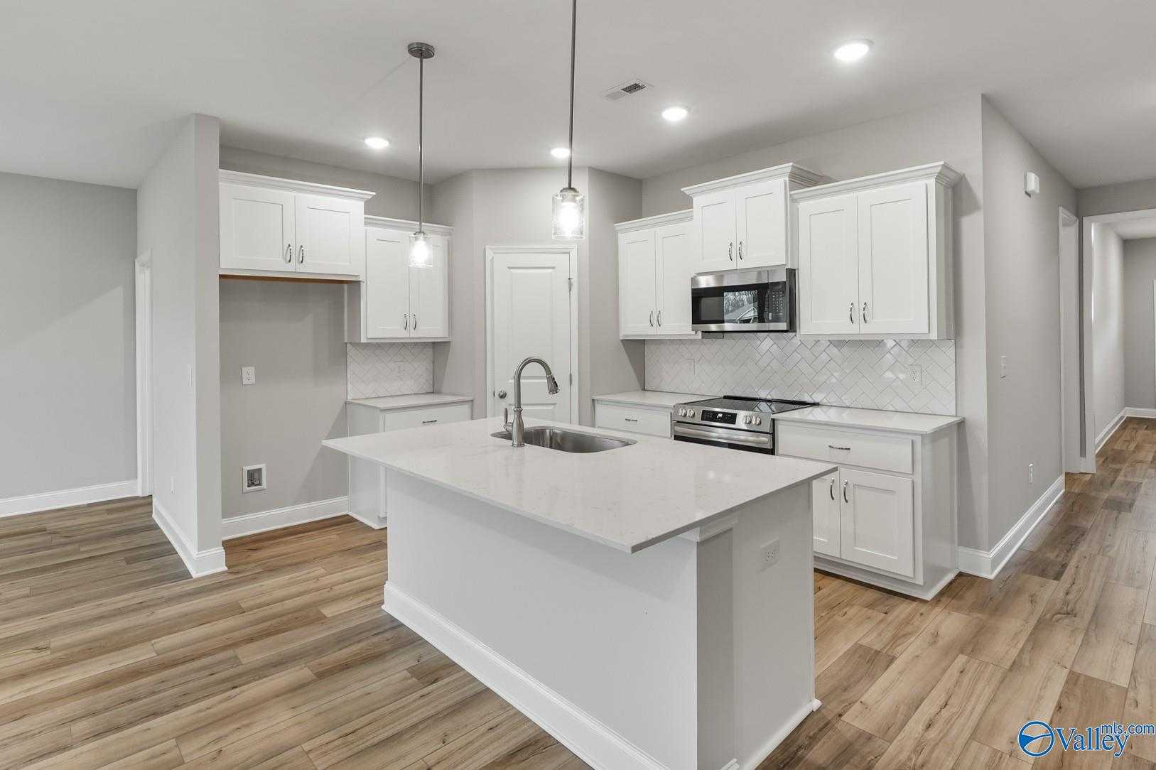 Bright white kitchen with quartz island, stainless appliances, subway tile backsplash in The Daphne D by Davidson Homes, Athens AL