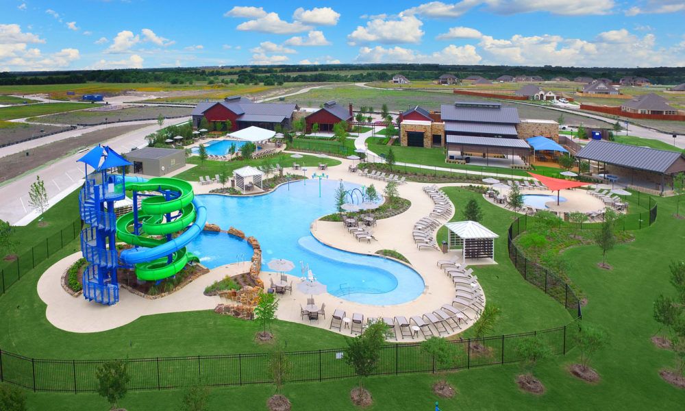 Resort-style swimming pool with twisting green waterslide at Heartland Texas community by Davidson Homes, lounge seating and cabanas