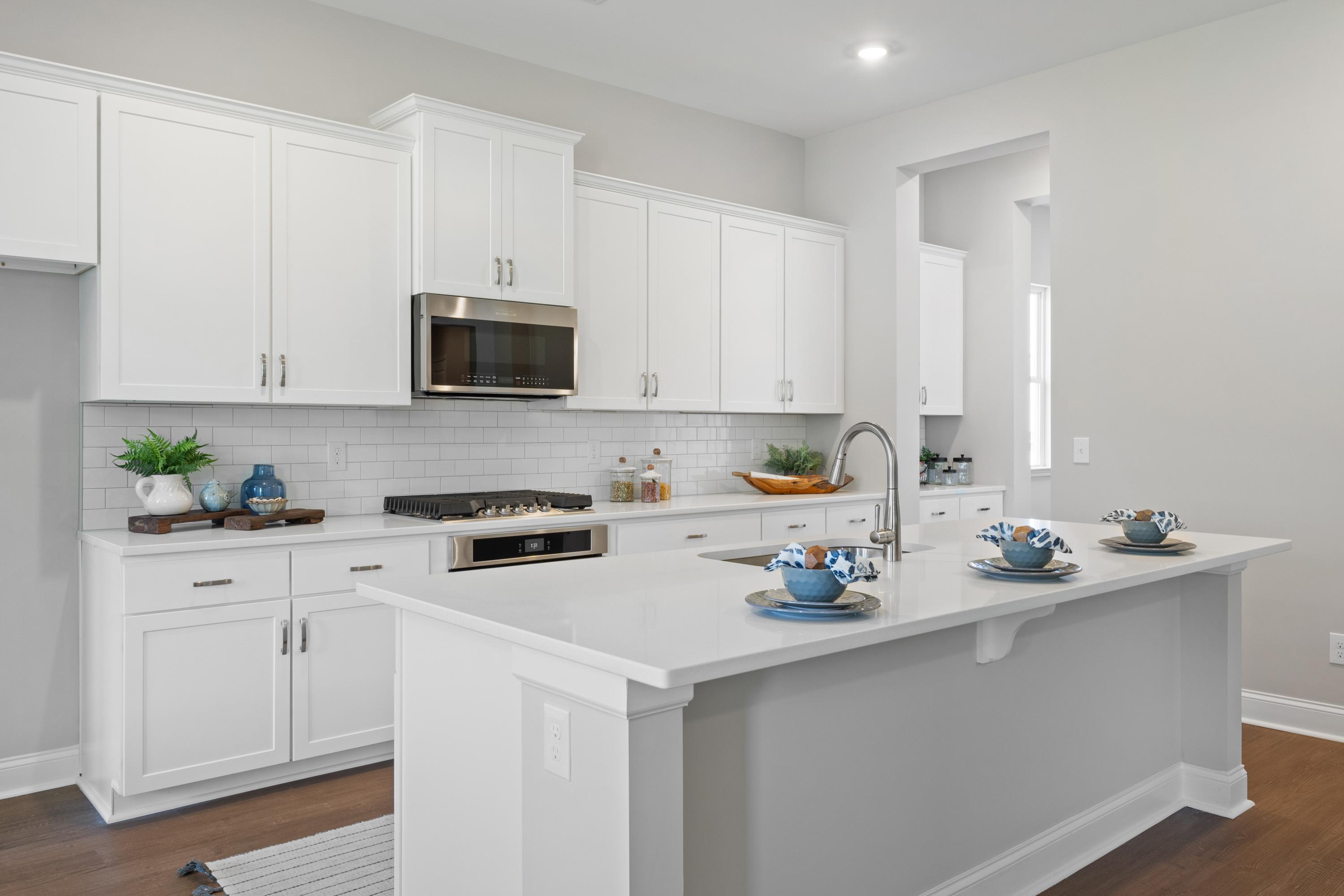 Modern kitchen in The Haven D home with white shaker cabinets, stainless steel appliances, and spacious island