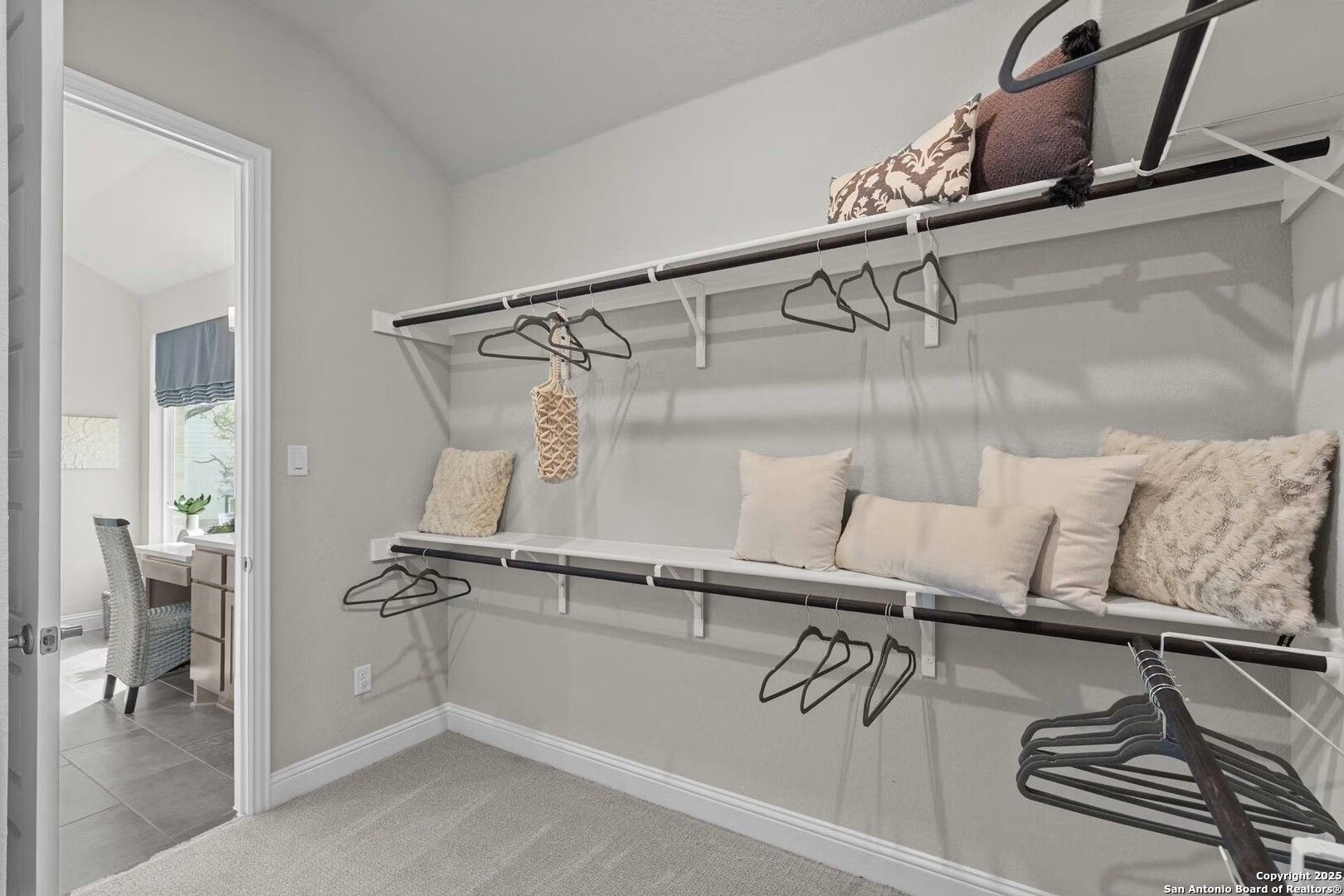 Spacious walk-in closet with built-in shelving, pillows, and hanging rods in master suite of Davidson Homes The Garner B, Castroville, Texas