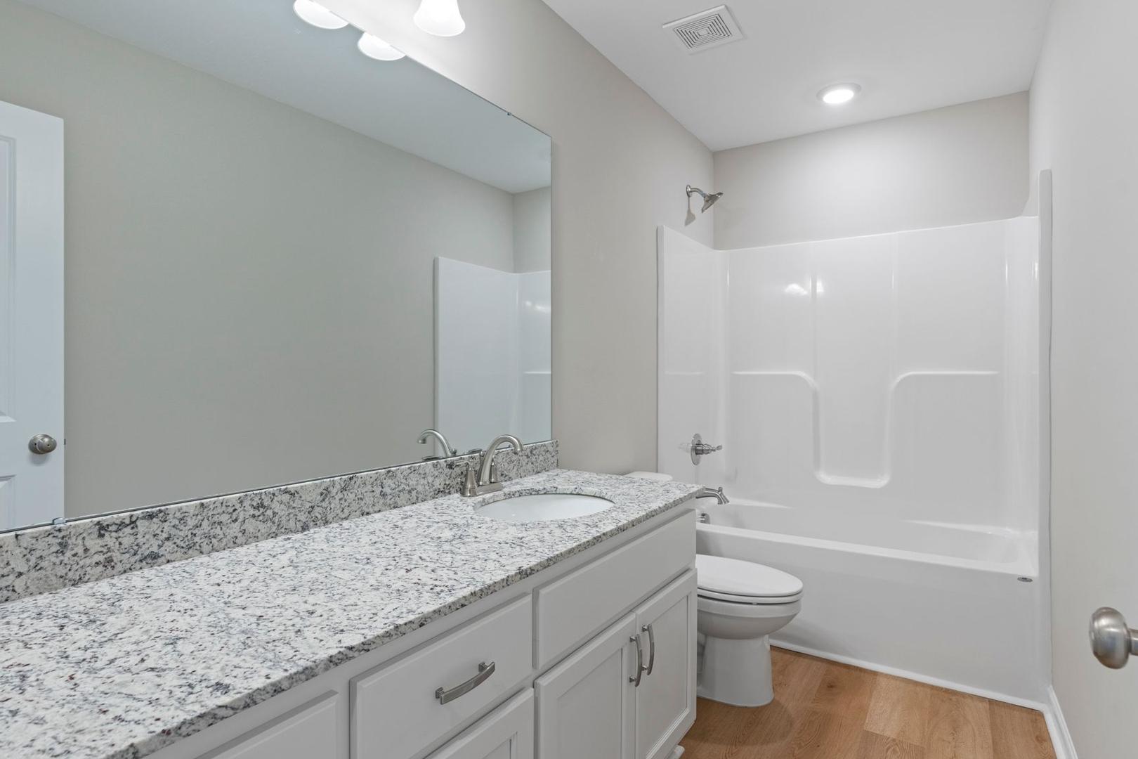 Secondary bathroom in The Stella A by Davidson Homes featuring granite vanity, separate tub, and walk-in shower