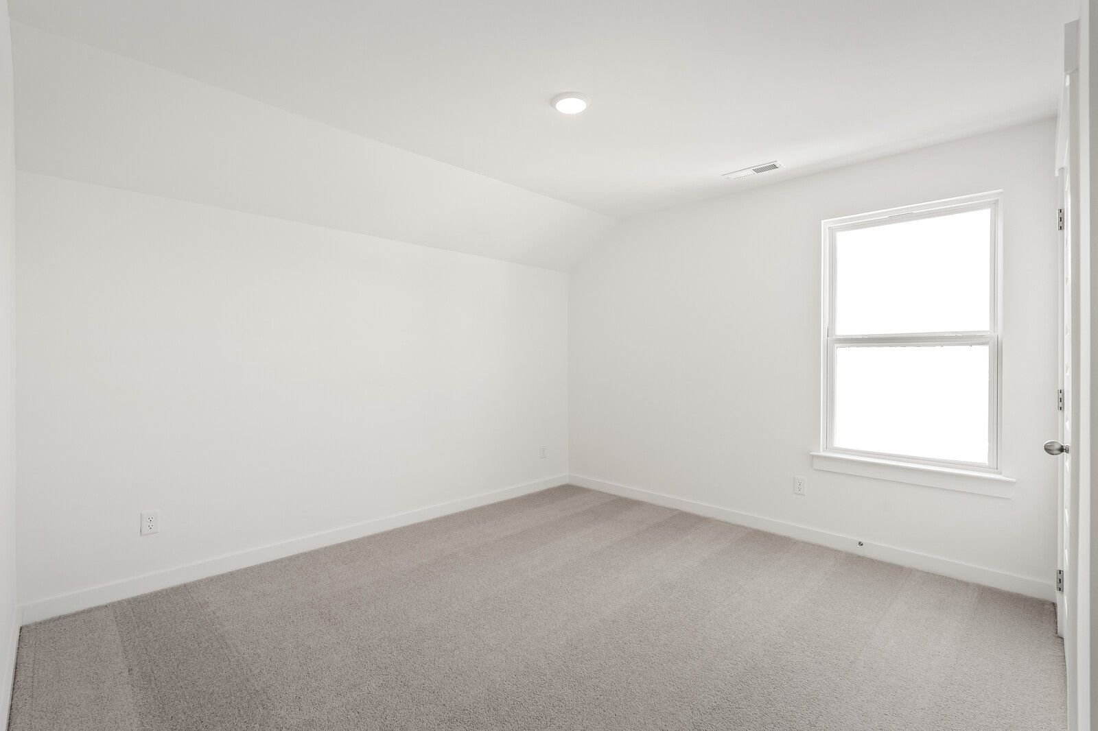 Bright empty bedroom with white walls, gray carpet, and large window in Davidson Homes The Ash A, Gallatin, TN