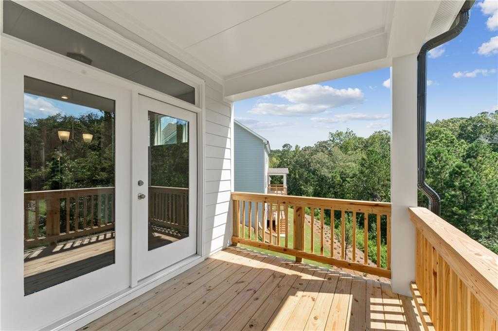 Covered wooden deck with French glass doors and railing overlooking lush woods in Davidson Homes The Ash B, Riverwood, Dallas, GA