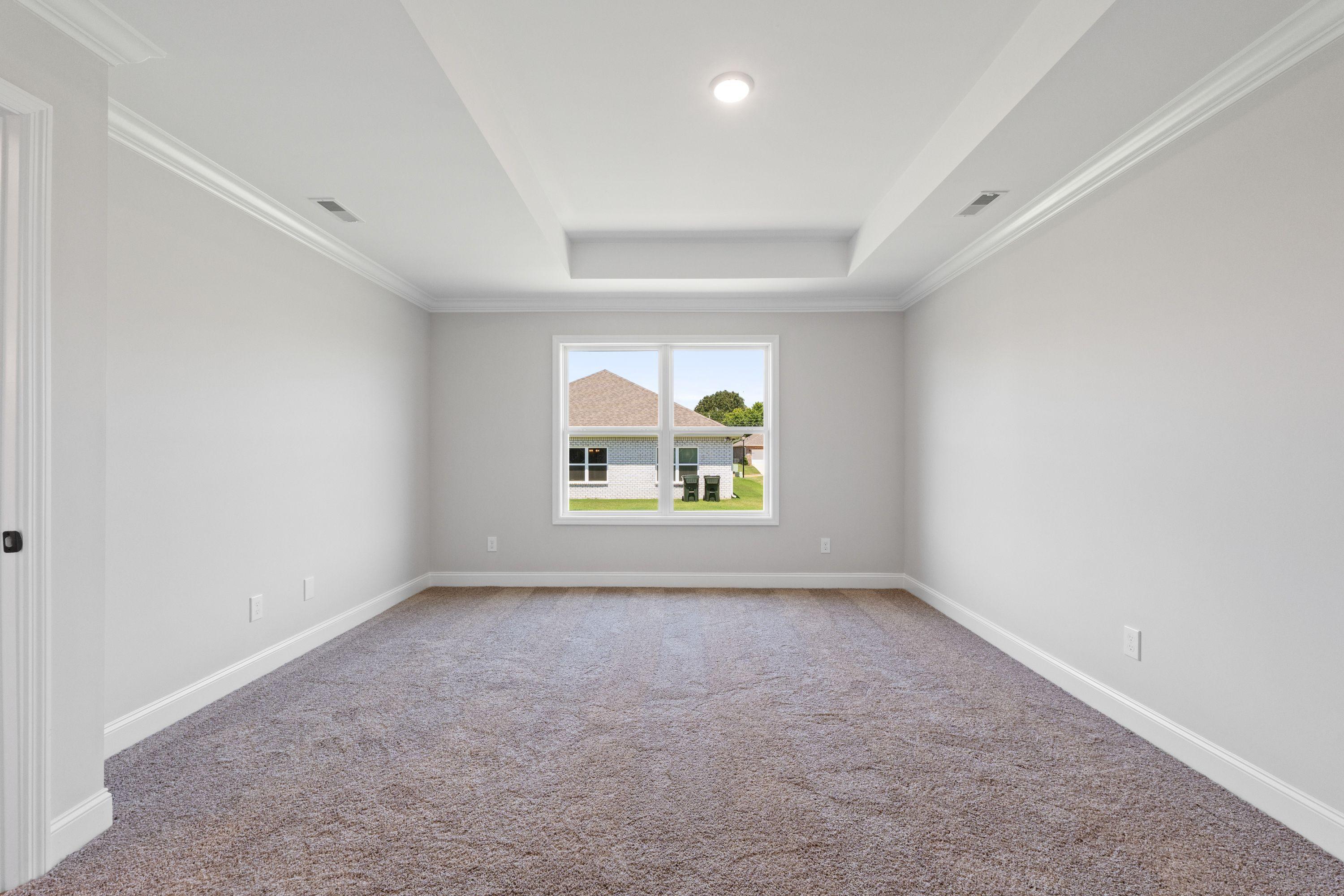 Spacious bedroom in The Holly C floor plan featuring neutral paint, plush carpeting, and a tray ceiling.