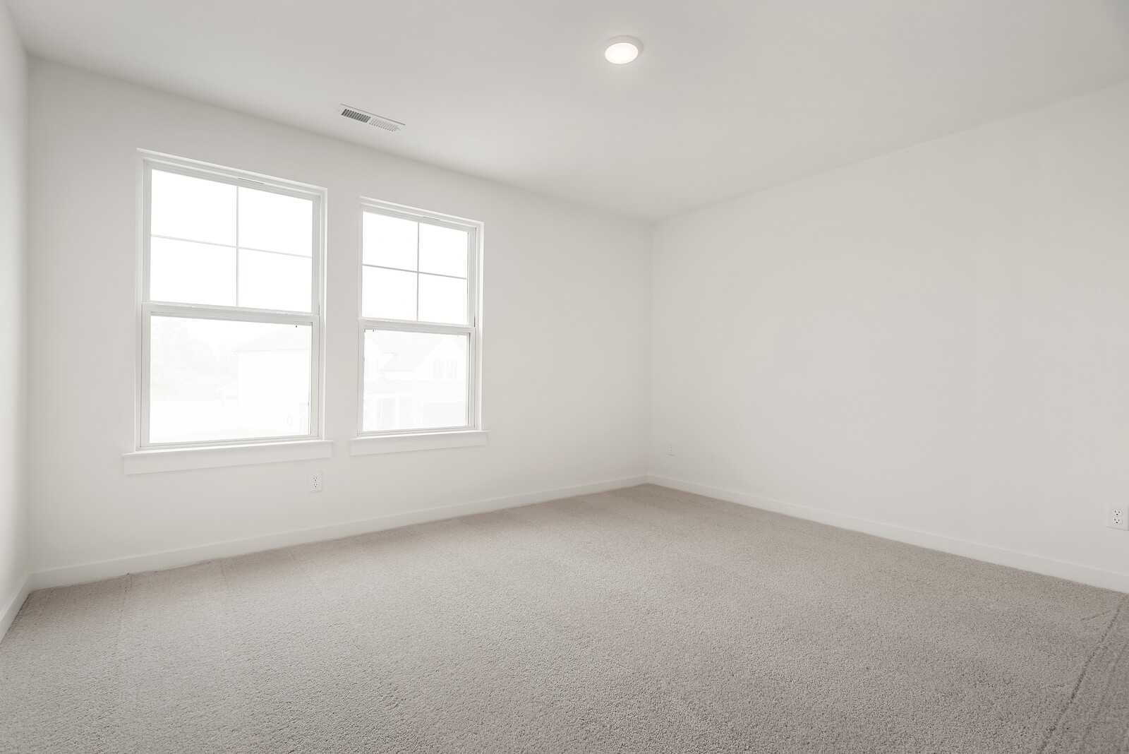 Bright empty bedroom with white walls, double windows, neutral carpet in Davidson Homes The Logan C, Gallatin, TN