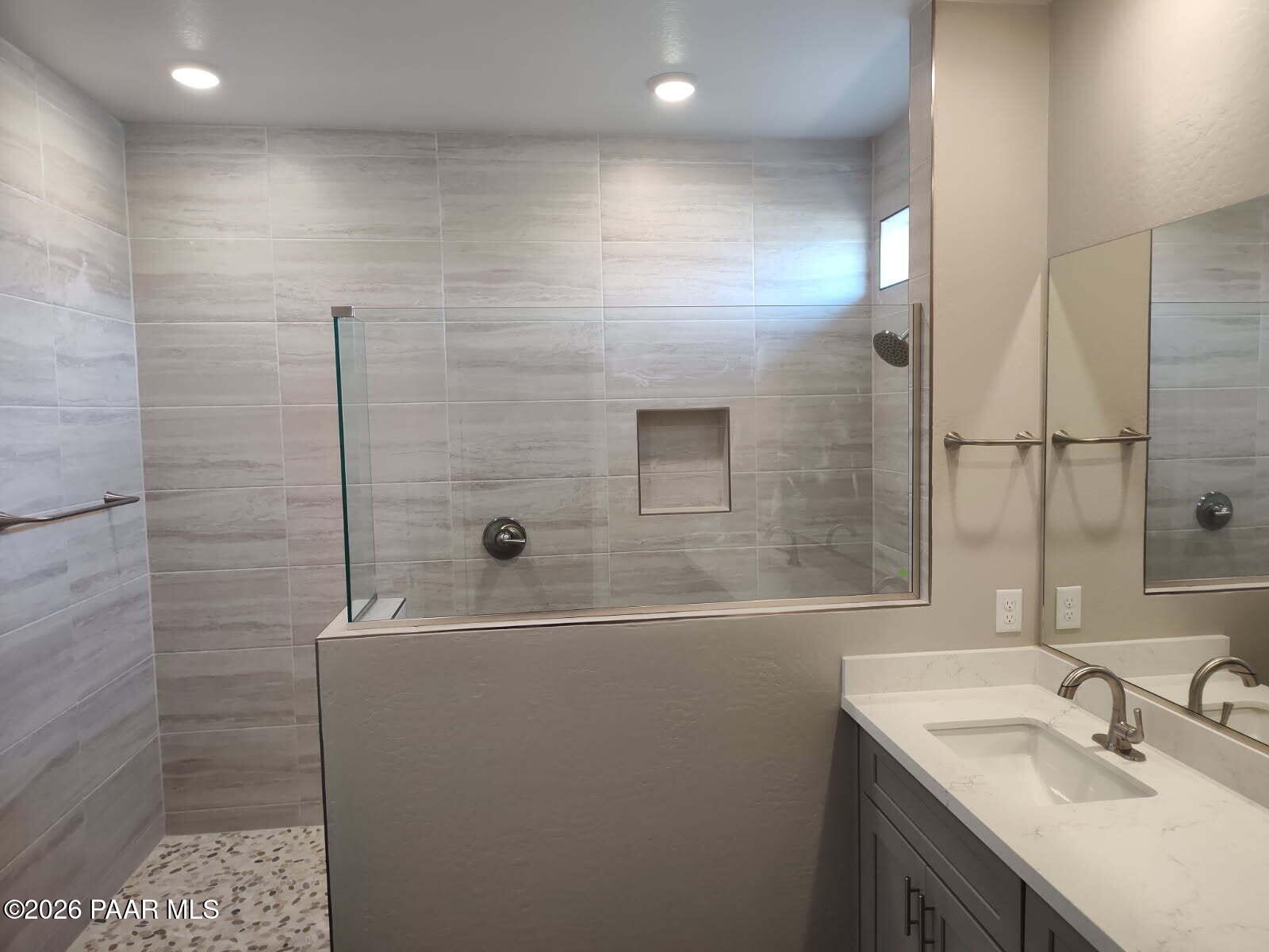Modern master bathroom featuring gray porcelain tile shower, pebble floor, double quartz vanity in Davidson Homes Harmony C, Prescott Valley AZ