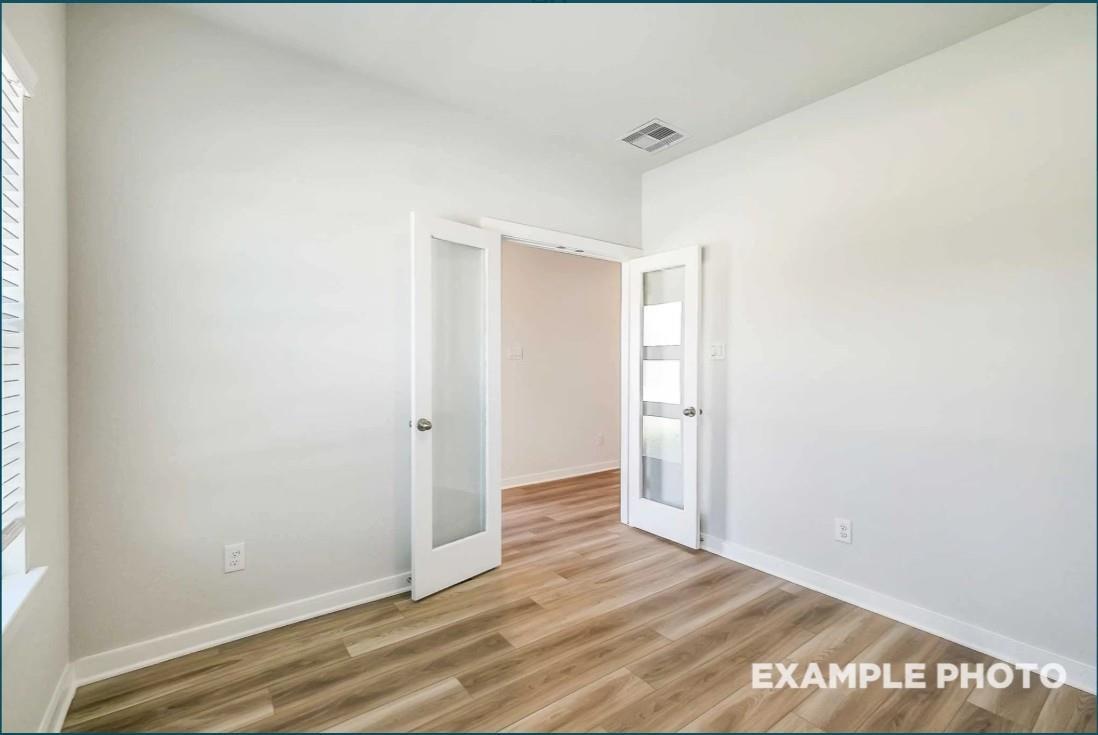 Open frosted glass doors in bright white entryway with light wood floors, Davidson Homes Riviera C in Dayton, Texas