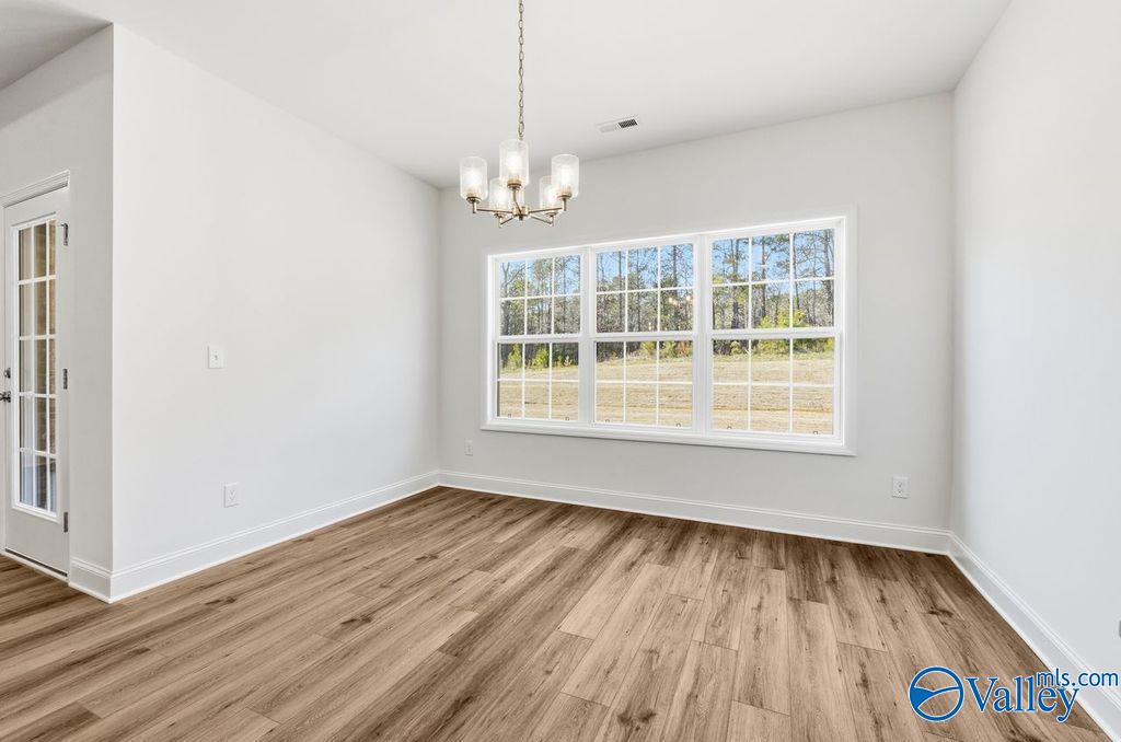 Bright dining room with hardwood floors, chandelier, and large windows to wooded view in The Montgomery, Davidson Homes, Hartselle AL