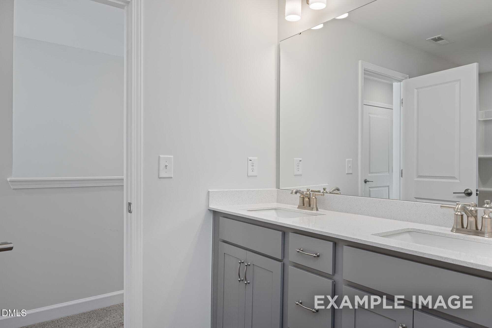 Modern double vanity bathroom with gray cabinets, white counters and mirrors in Davidson Homes The Cypress B II, Angier, NC