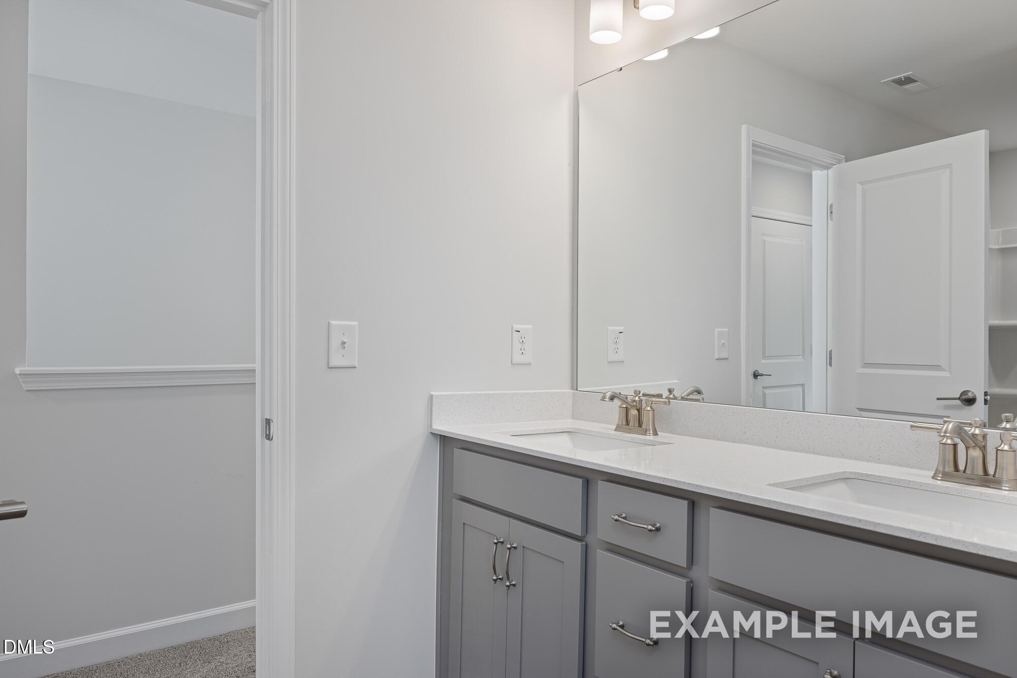 Modern double vanity in master bath with gray shaker cabinets, quartz counters, and framed mirrors in Davidson Homes The Cypress B II, Angier, NC