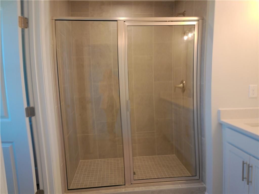 Modern frameless glass shower enclosure with beige tile surround in master bath, Davidson Homes The Marion C, Winder Georgia