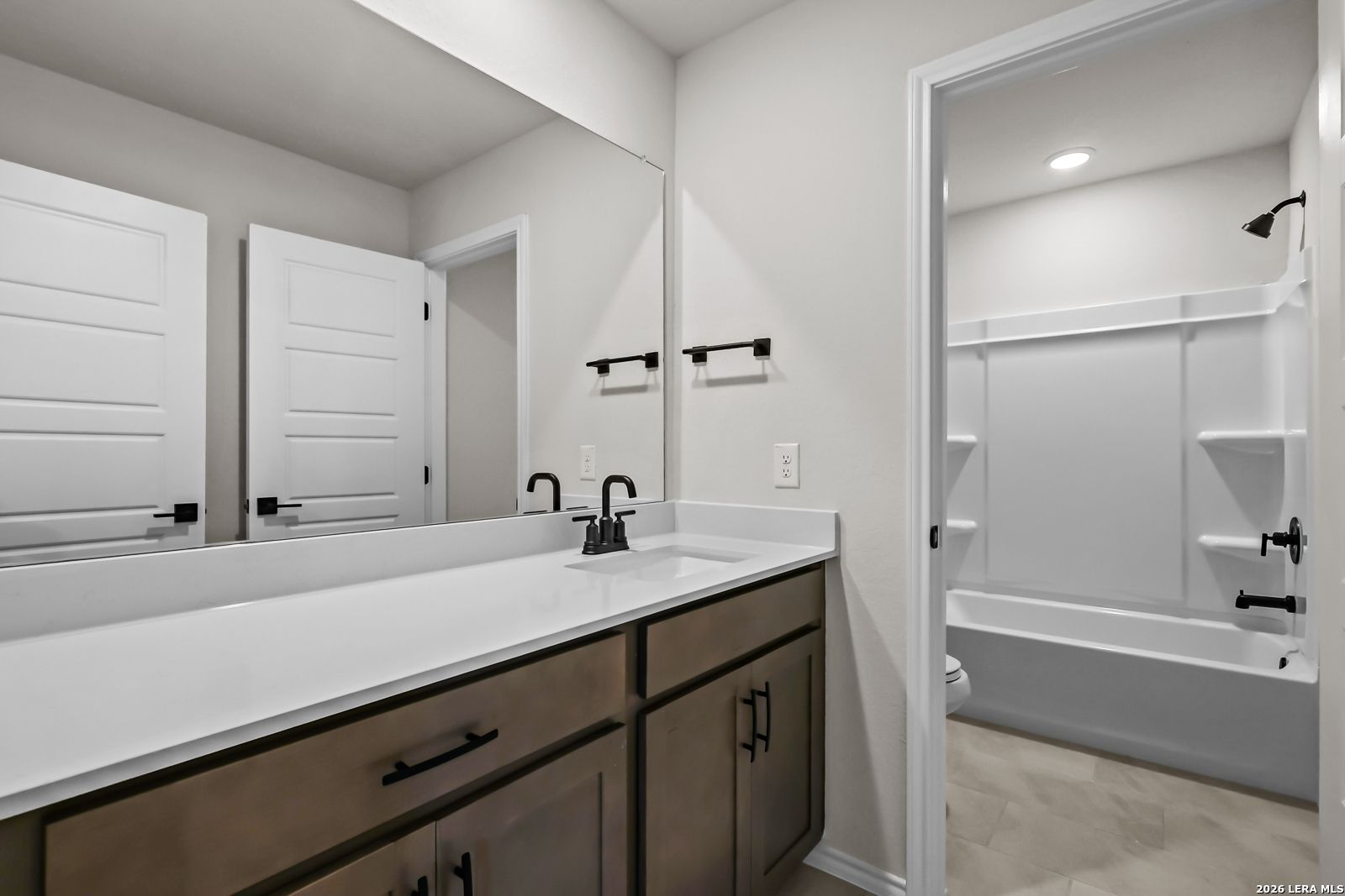 Modern bathroom with vanity, matte black fixtures, and tub-shower combo in The Douglas C home at Hannah Heights, Seguin, TX.