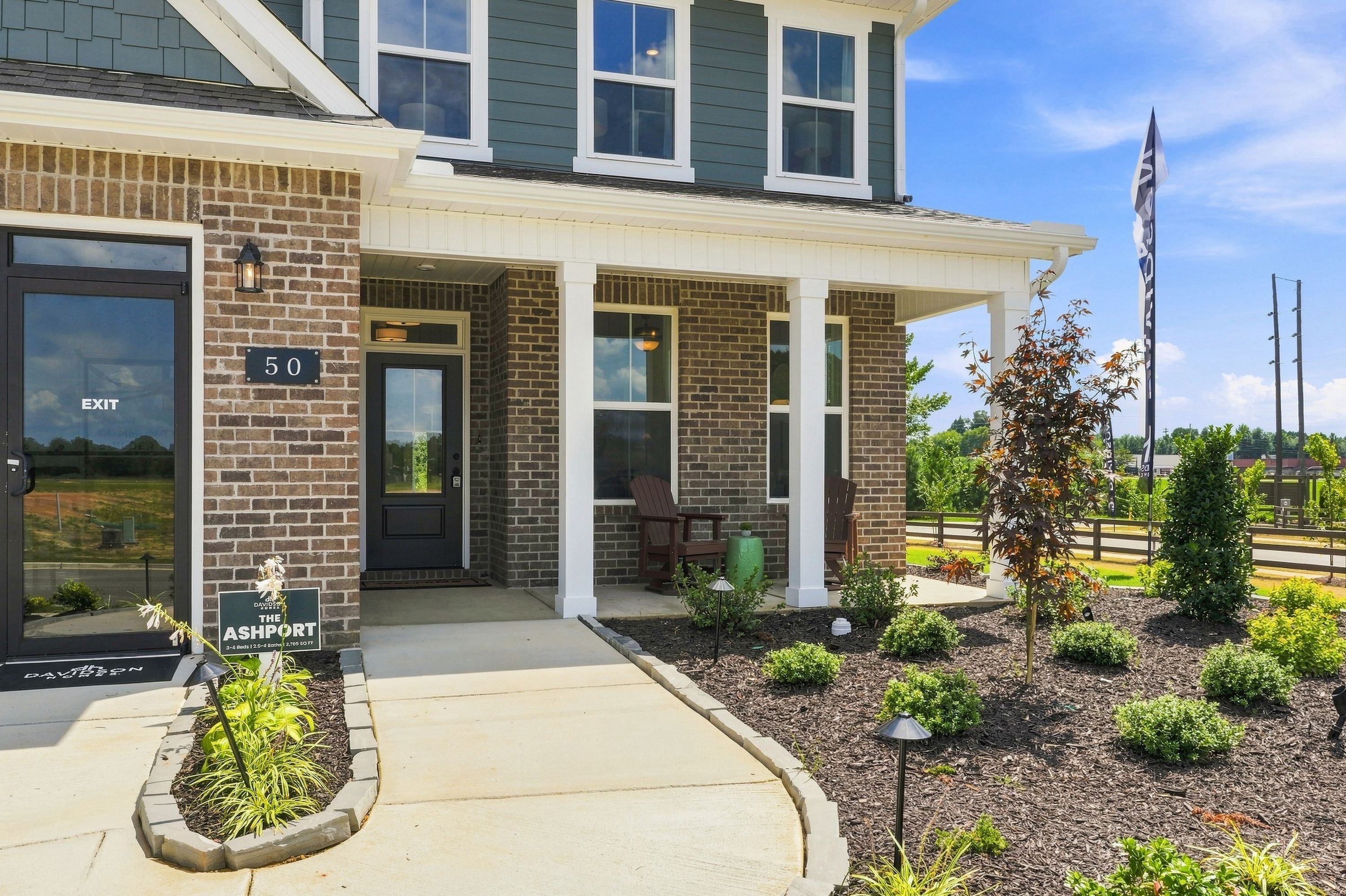 Ashport model home exterior at Little Creek in Arab, Alabama, featuring brick facade and covered front porch by Davidson Homes.