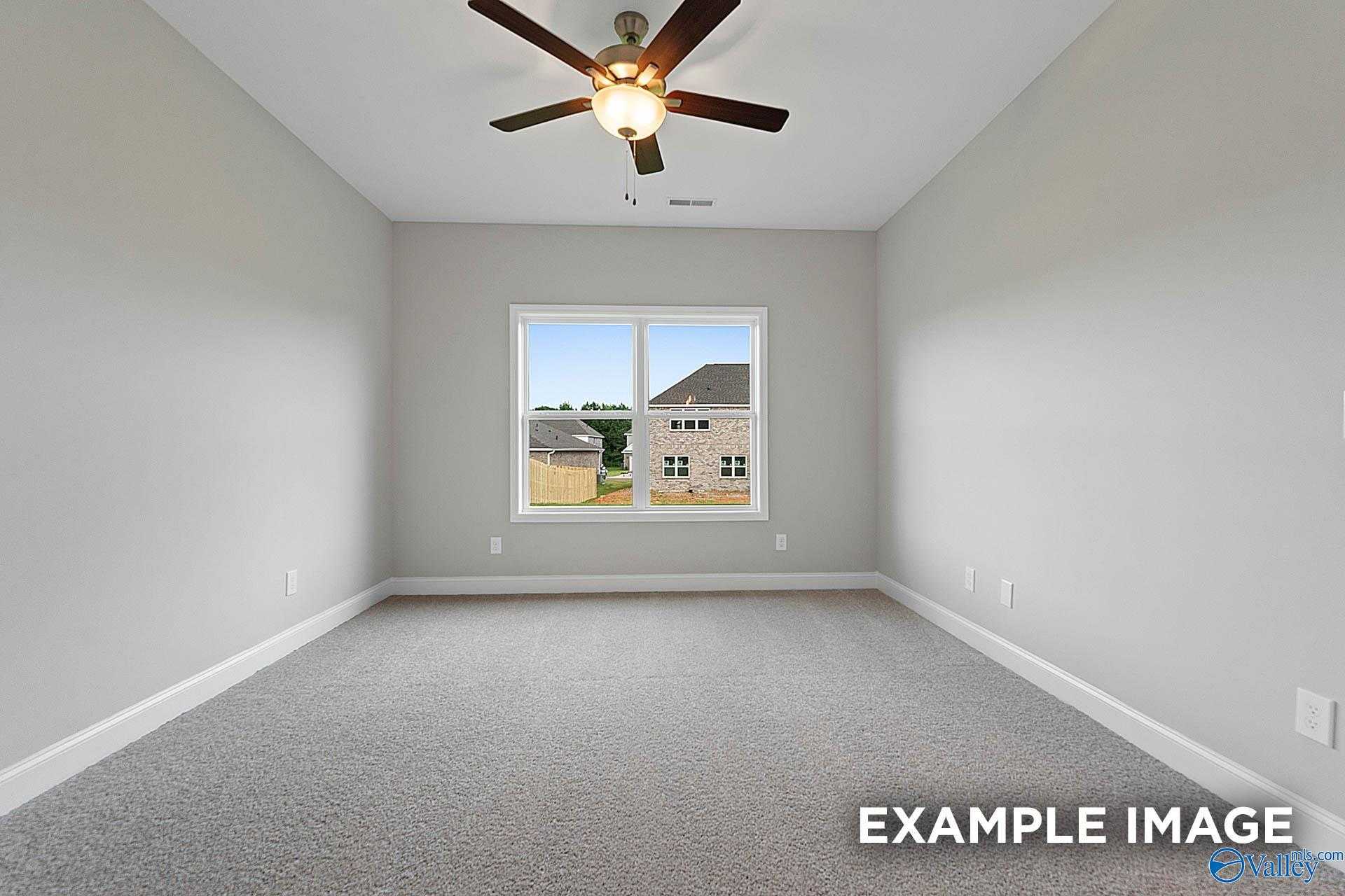Bright empty bedroom with ceiling fan, large window to neighborhood view in Davidson Homes The Franklin E, Hazel Green, Alabama