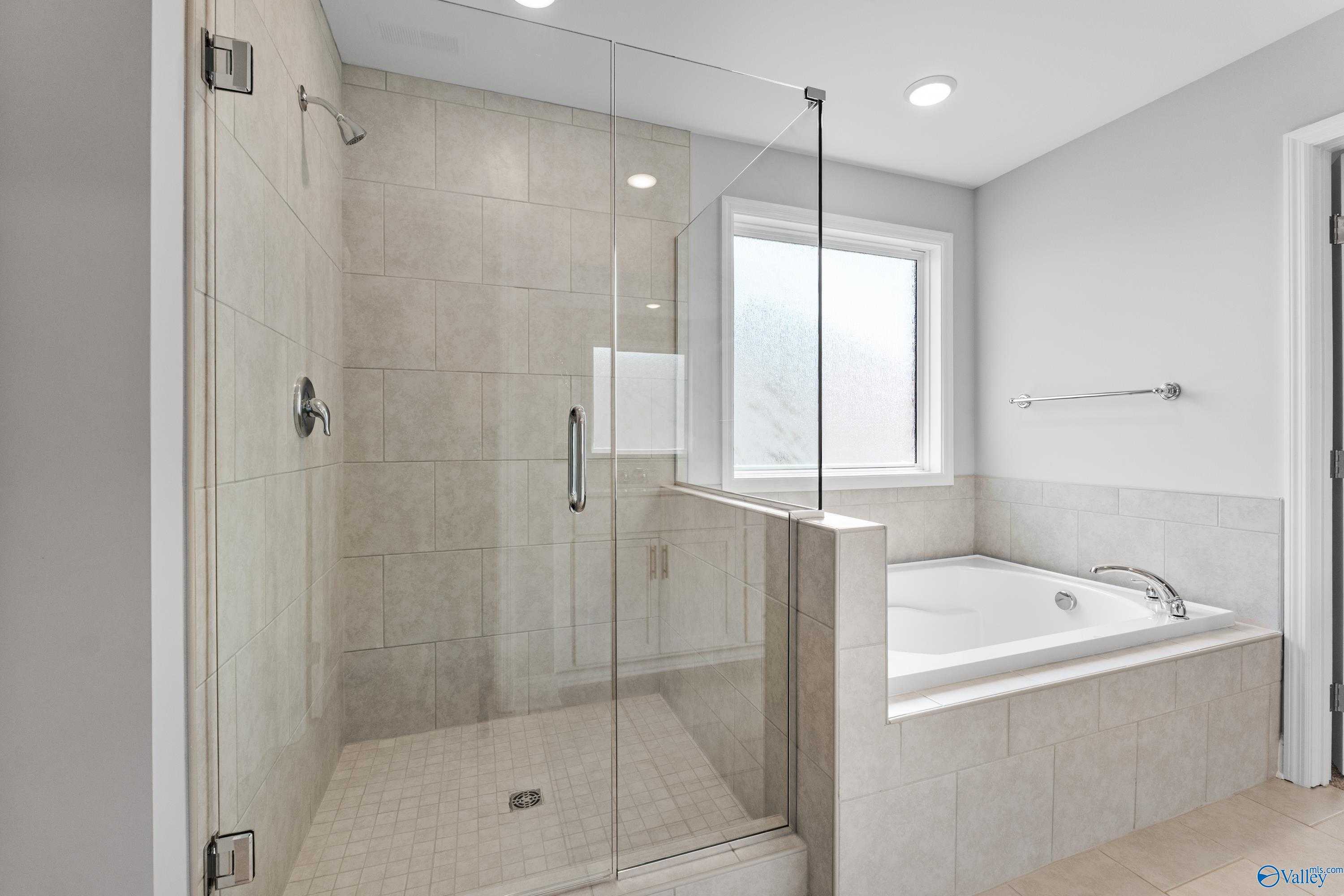 Modern master bathroom featuring frameless glass shower and soaking tub in Davidson Homes The Madison A, Toney, Alabama