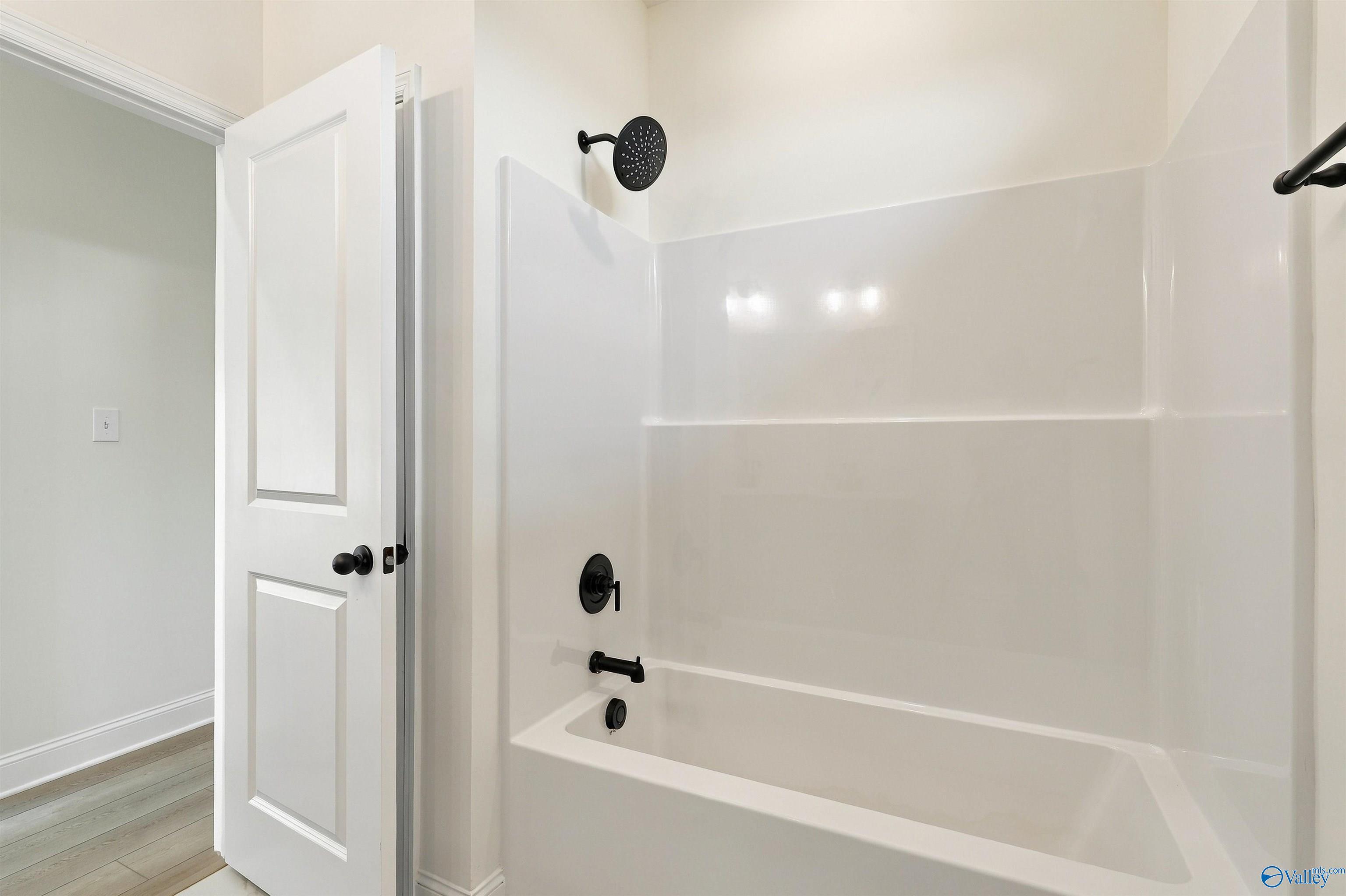 White bathtub with matte black shower fixtures and rain showerhead in Davidson Homes The Valencia bathroom in Huntsville, Alabama