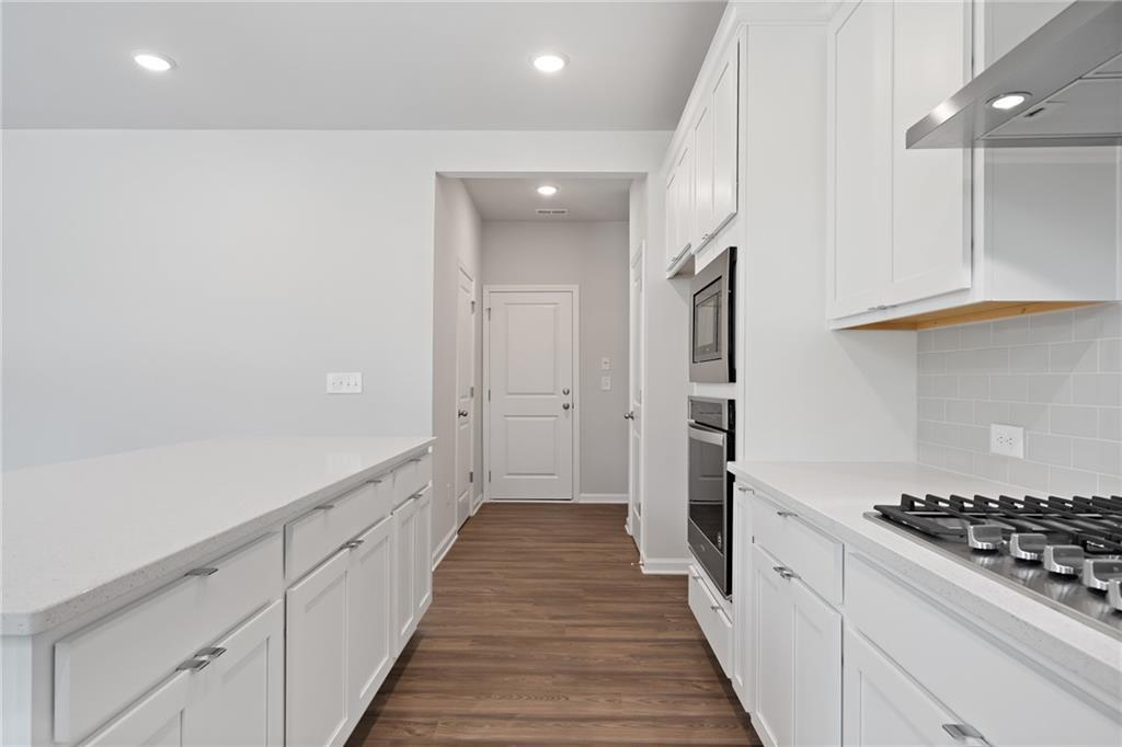 Modern white kitchen with island, stainless gas range, double ovens in Davidson Homes The Hickory A, Winder, GA