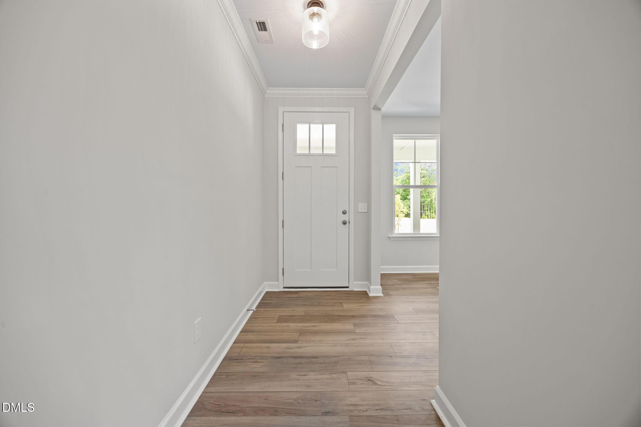 Bright foyer featuring white front door with glass panels, light gray walls, hardwood floors in The Willow D by Davidson Homes, Wendell, NC