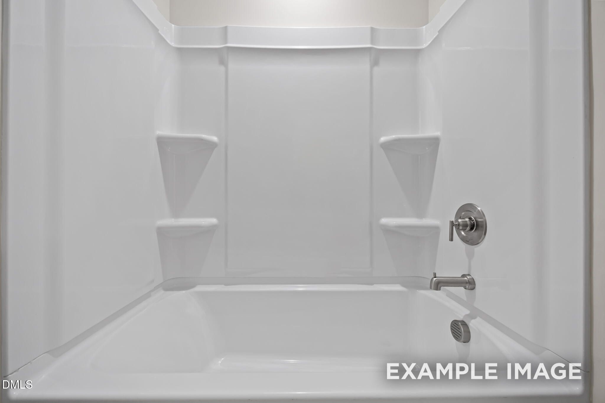 White tub shower combo with seamless surround, built-in shelves, and chrome faucet in Davidson Homes The Avery bathroom, Knightdale, NC