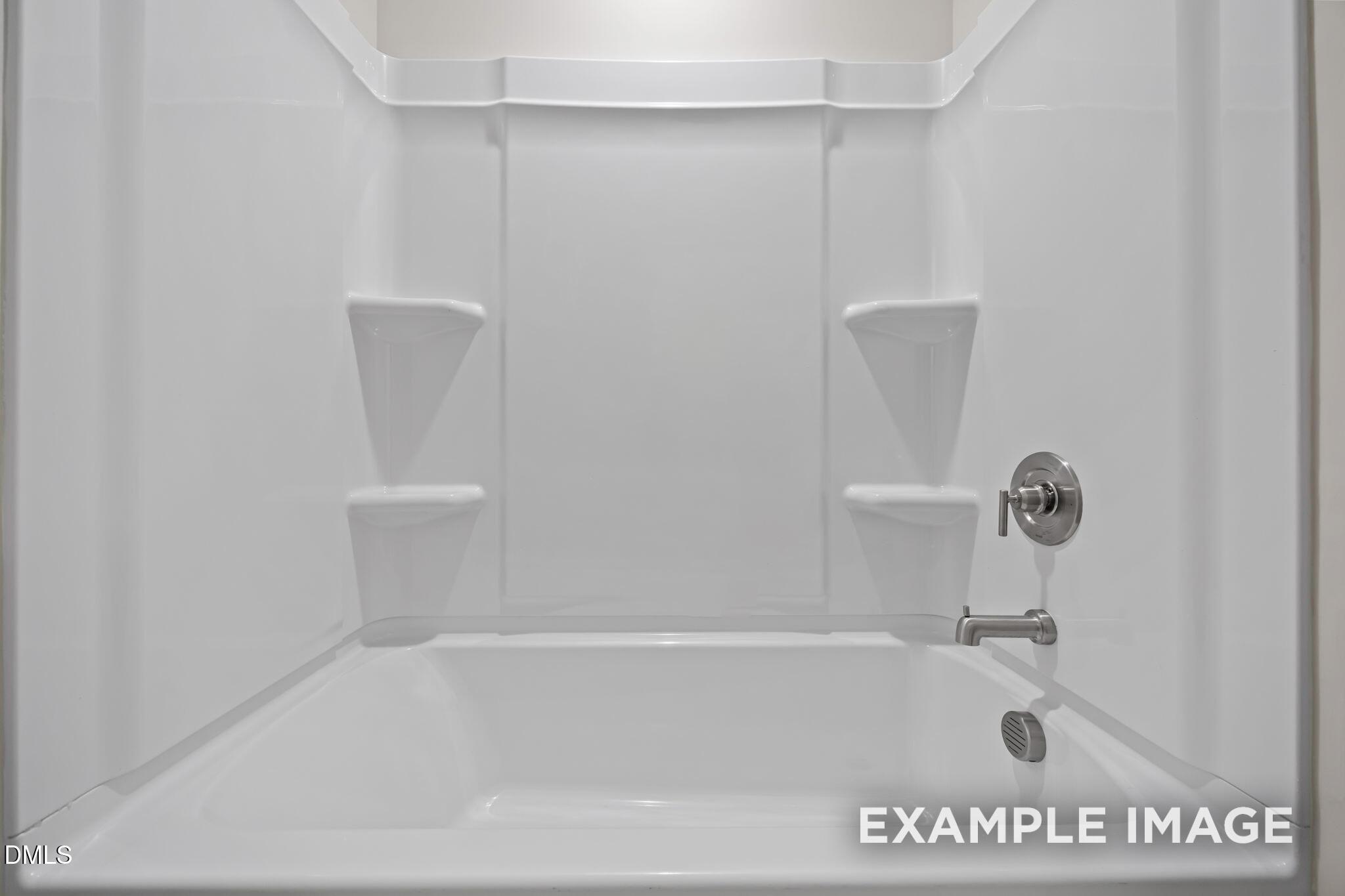 White tub shower combo with seamless surround, built-in shelves, and chrome faucet in Davidson Homes The Avery bathroom, Knightdale, NC