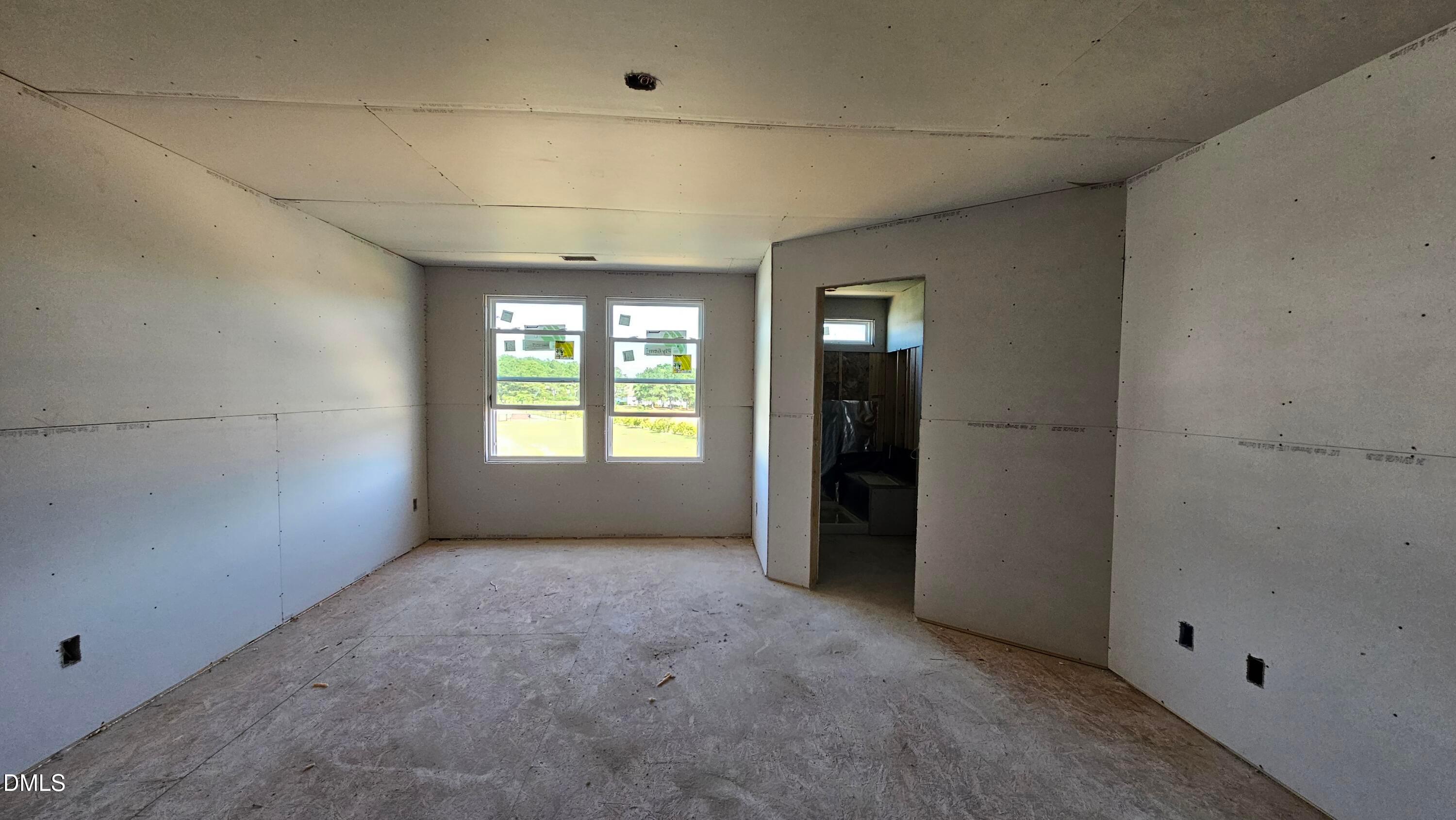 Unfinished bedroom with drywall and natural light in The Graham Interior floor plan at Springvale, Fuquay-Varina.