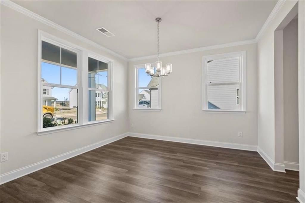 Bright dining area with wood-style flooring and modern chandelier in The Ash C floor plan at Wehunt Meadows, Hoschton.