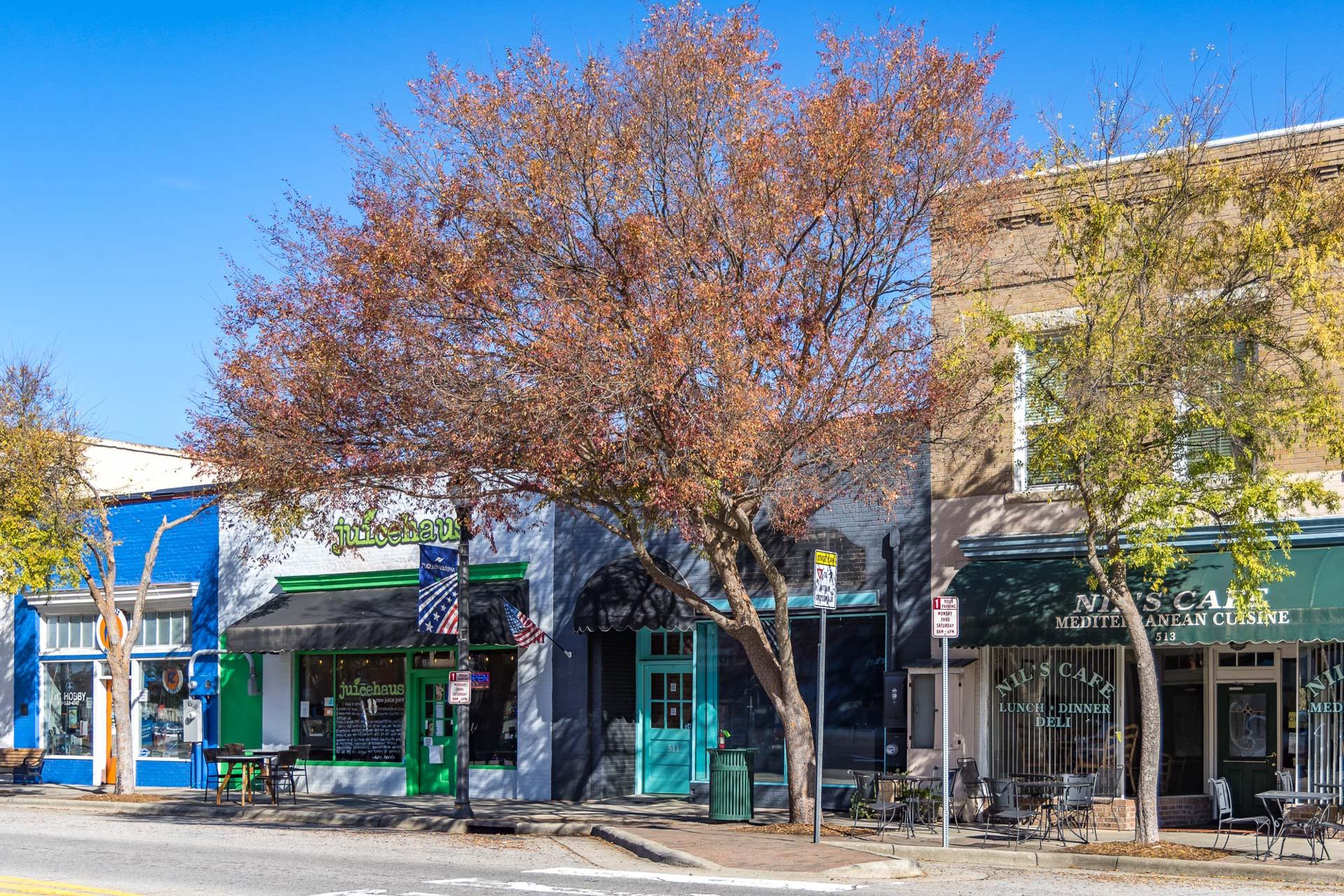 Quaint Fuquay-Varina NC street with colorful storefronts, Main Street Cafe awning, autumn trees, and outdoor bistro seating in Highland Forest