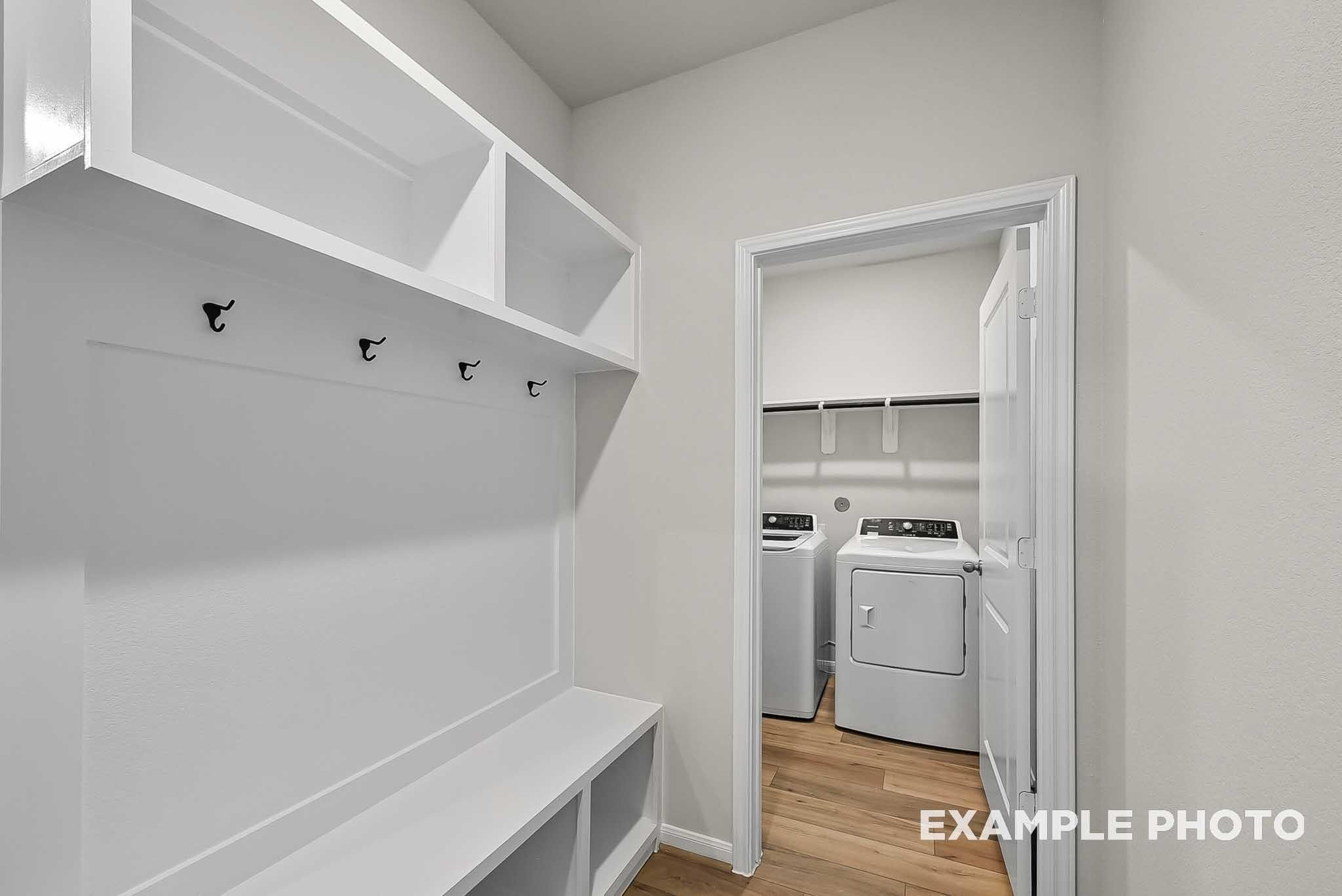 Mudroom with built-in bench and hooks leading to laundry room in The Blanco F floor plan at Spring Branch Crossing, Conroe.