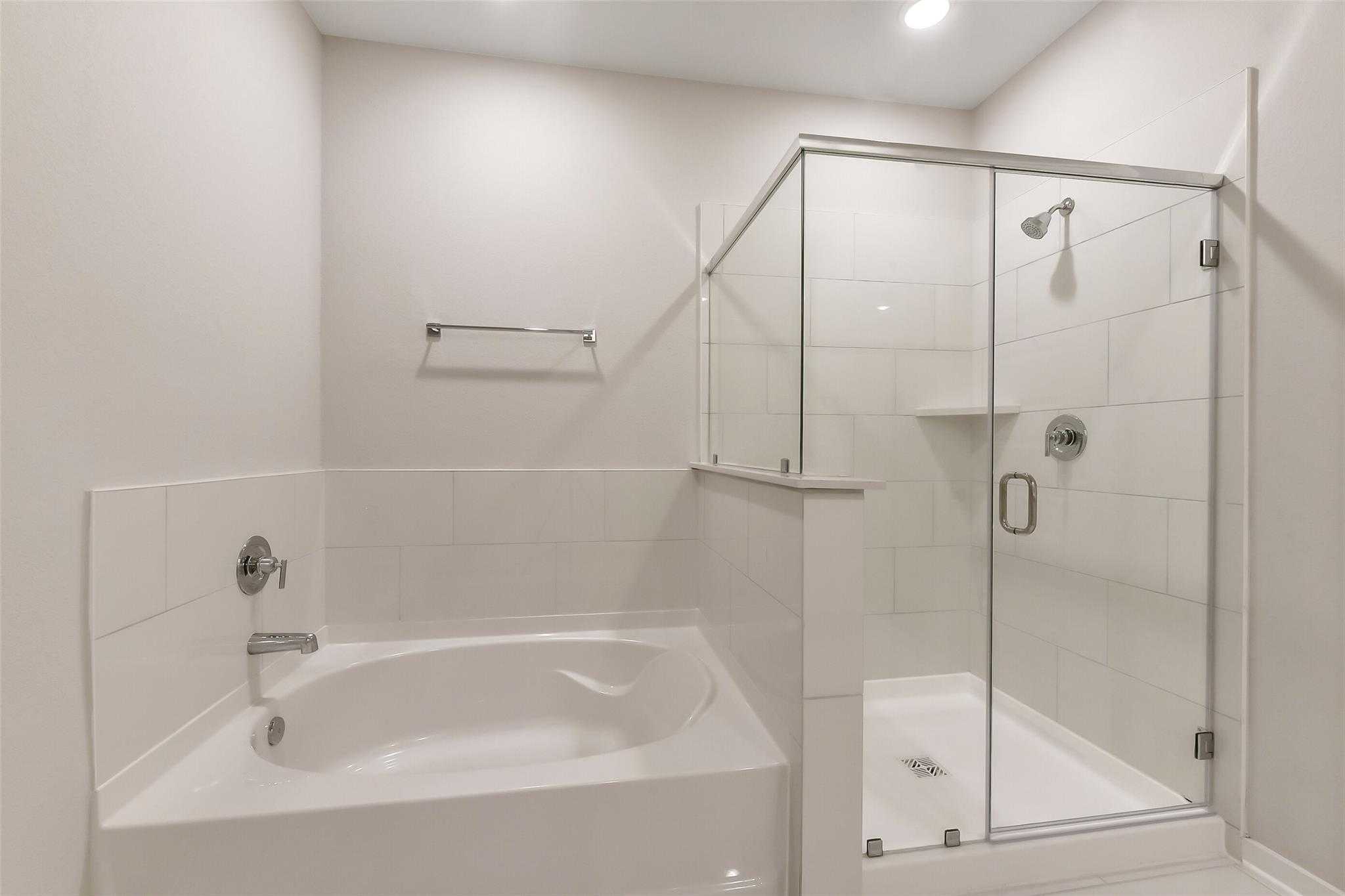 Elegant master bathroom with soaking tub and glass-enclosed walk-in shower in Davidson Homes The Laguna B, Sunterra, Katy, Texas
