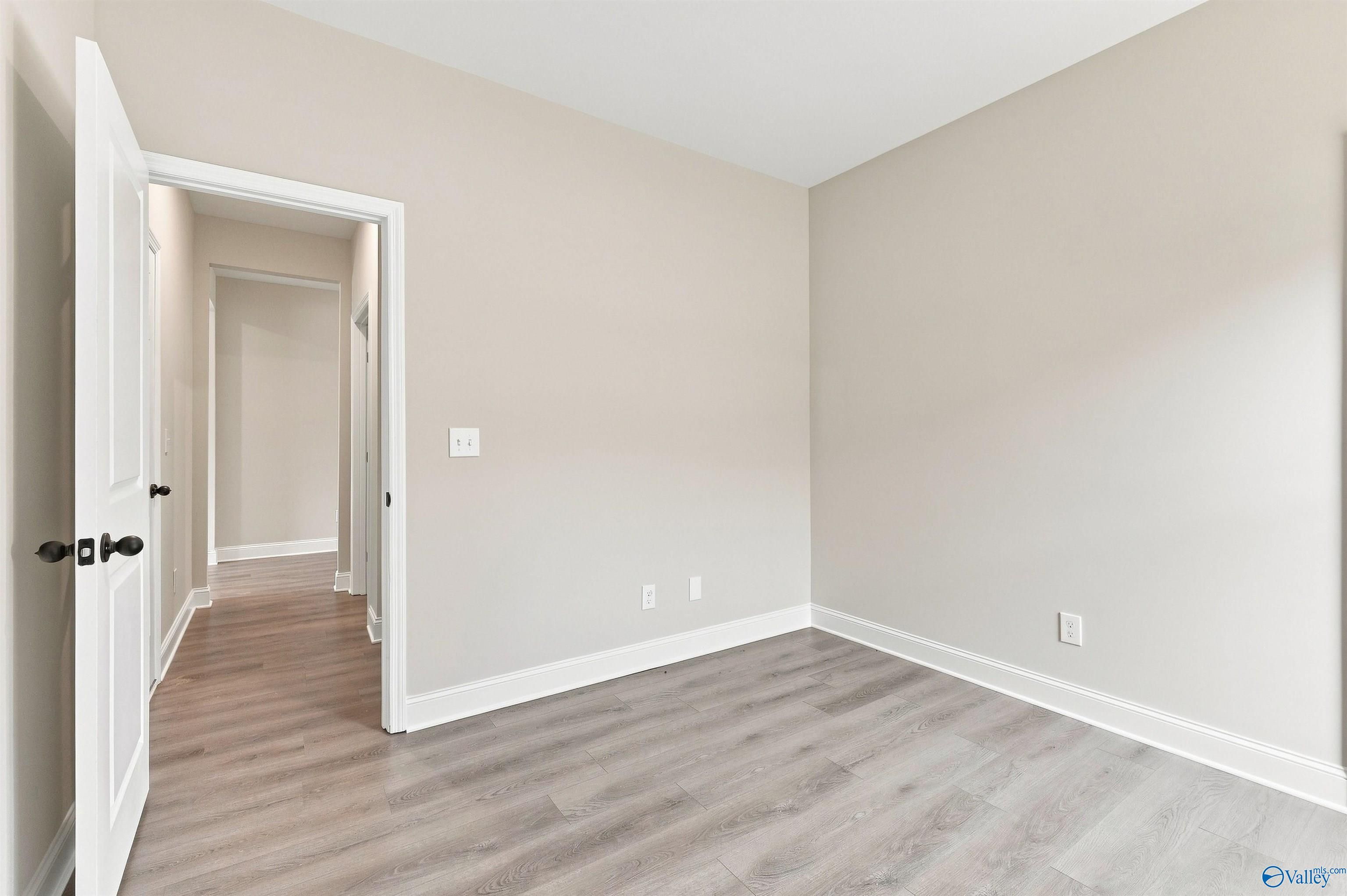Bright neutral bedroom with wood-look flooring in The Daphne floor plan by Davidson Homes in Spragins Cove, Huntsville.