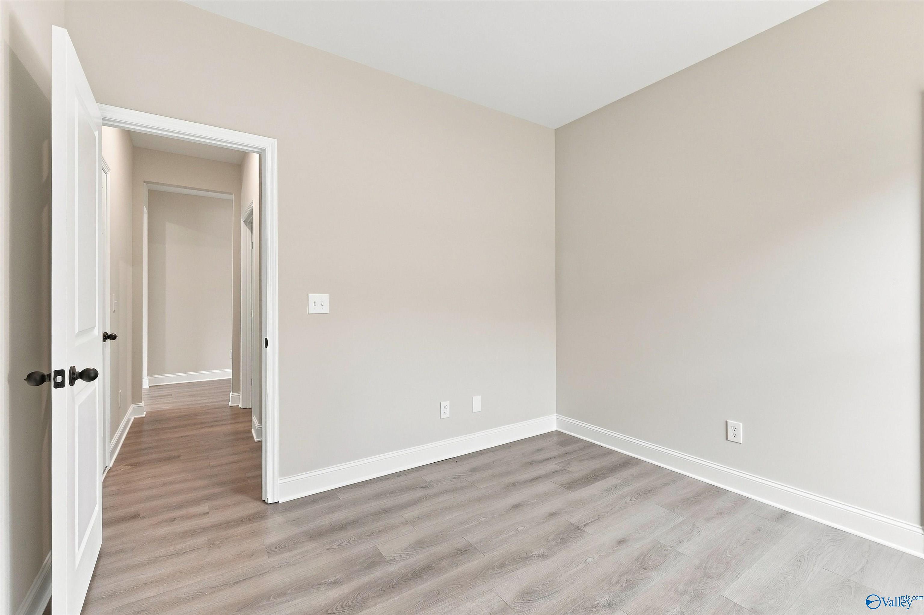 Bright neutral bedroom with wood-look flooring in The Daphne floor plan by Davidson Homes in Spragins Cove, Huntsville.